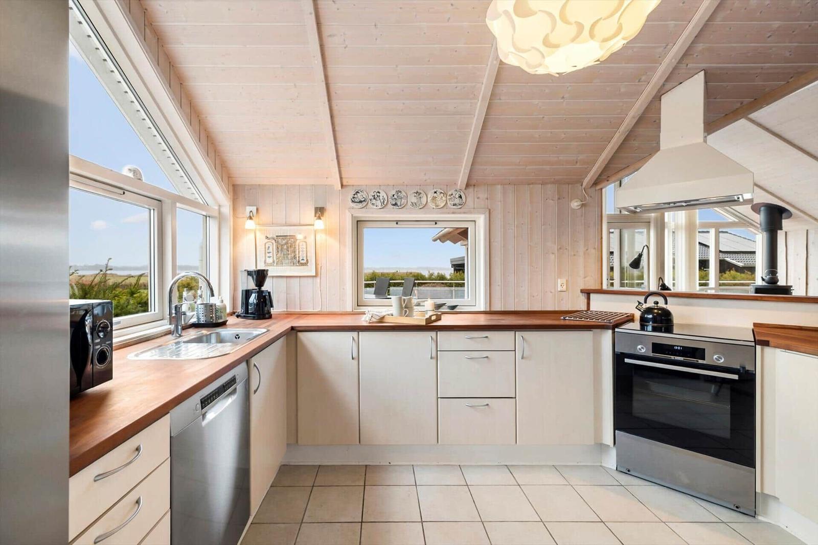 Kitchen with wooden countertop, stainless steel appliances, and windows with views.
