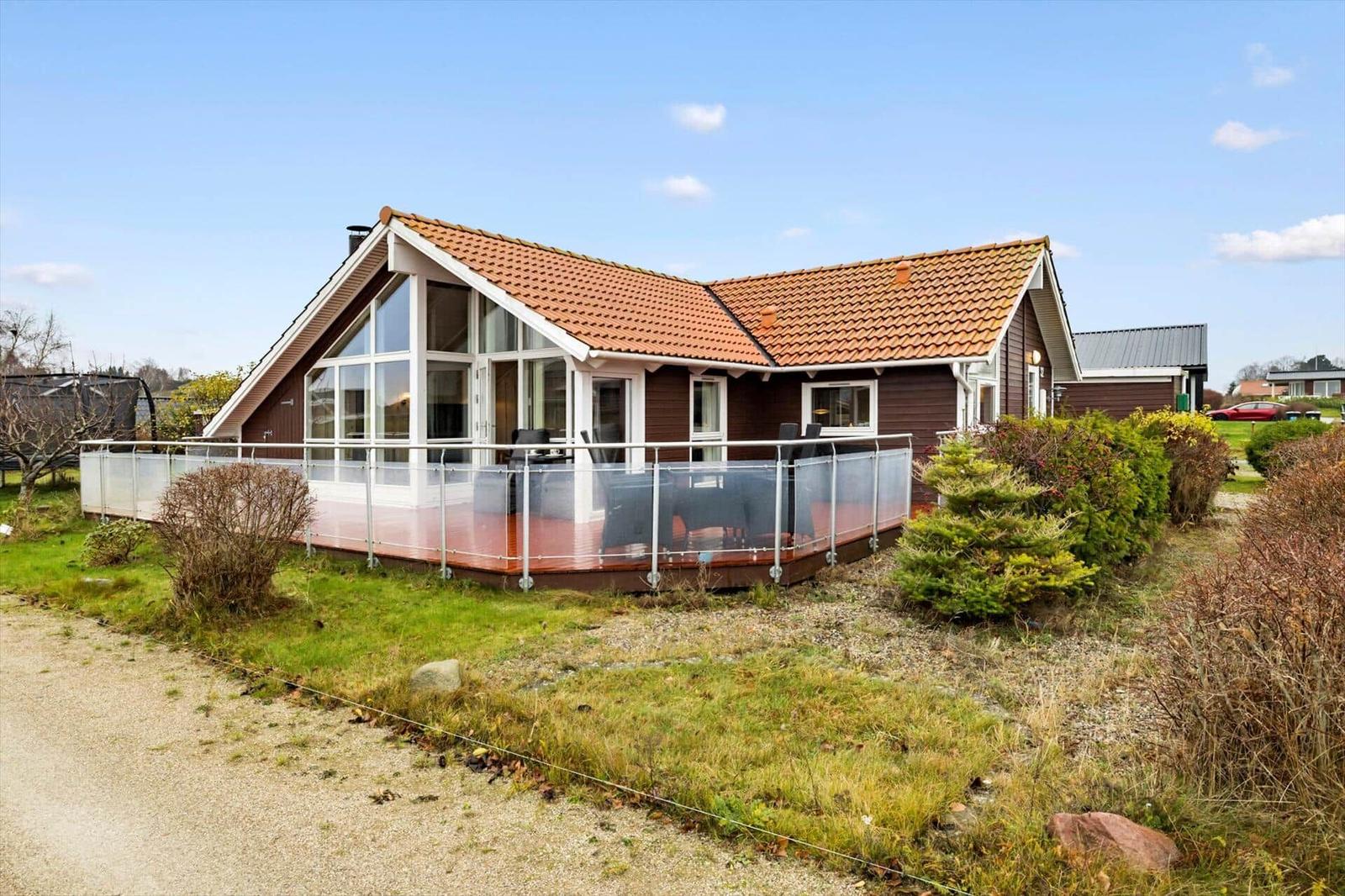 Wooden house with large balcony and terrace under blue sky.