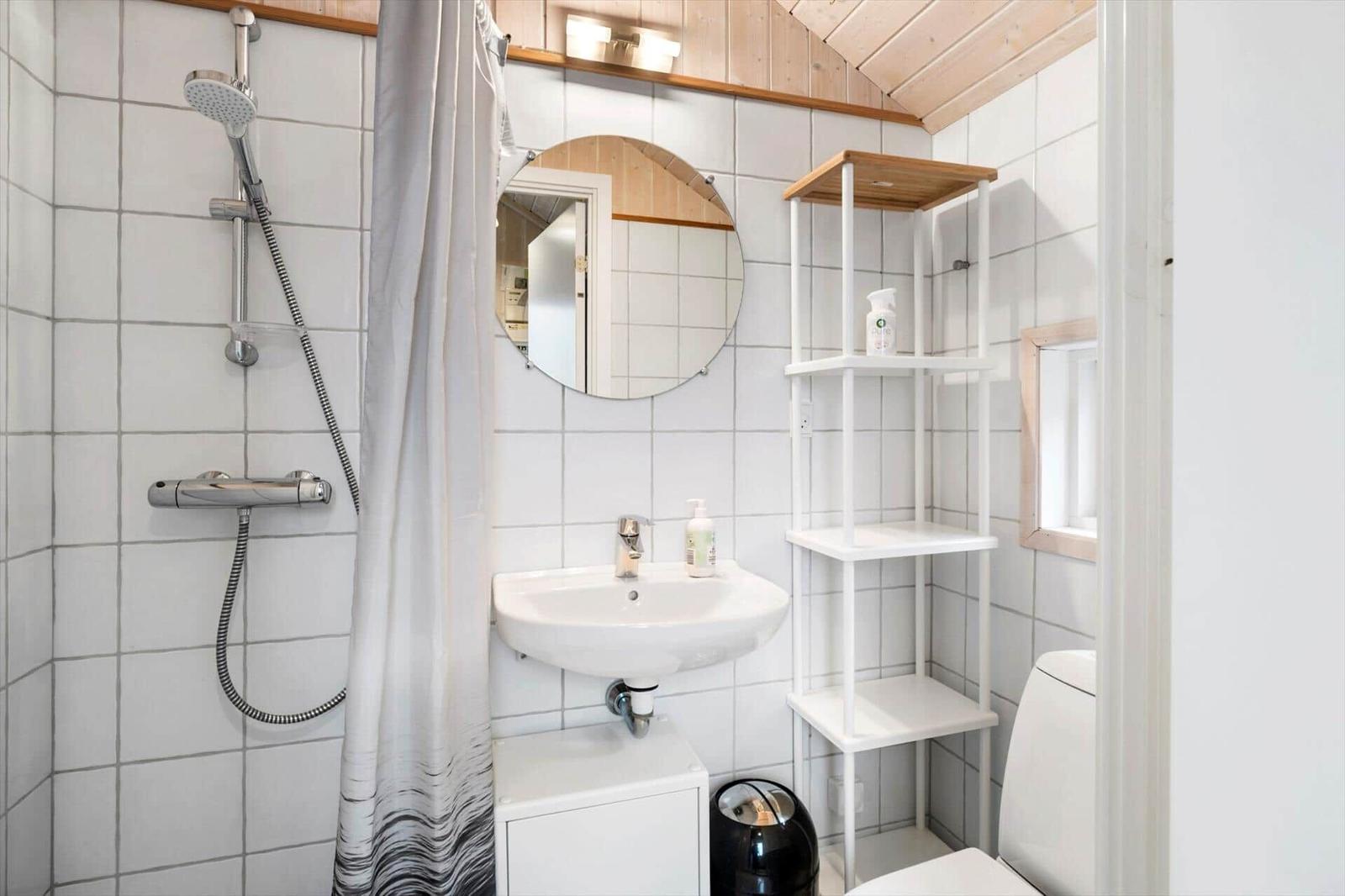 Bathroom with shower, sink, and toilet. White tiles and wooden ceiling.