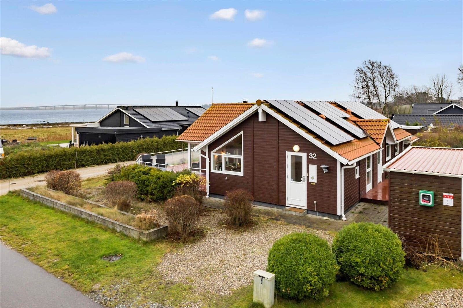 Wooden houses with solar panels and garden near the water.