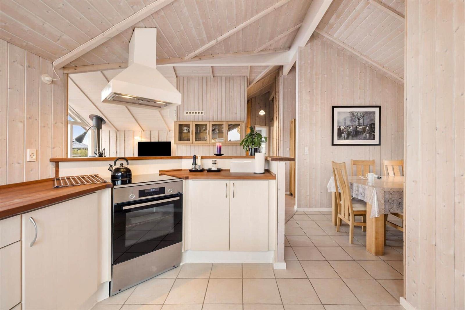 Kitchen with dining area, wooden walls, and stainless steel stove.