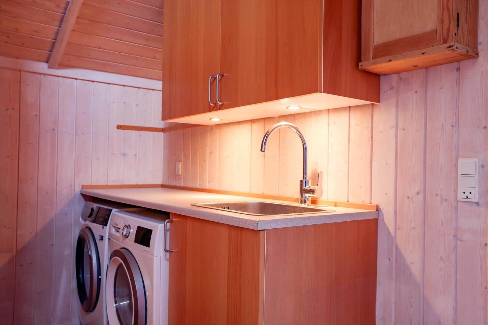 Kitchen area with sink, washing machine, and wooden fixtures.