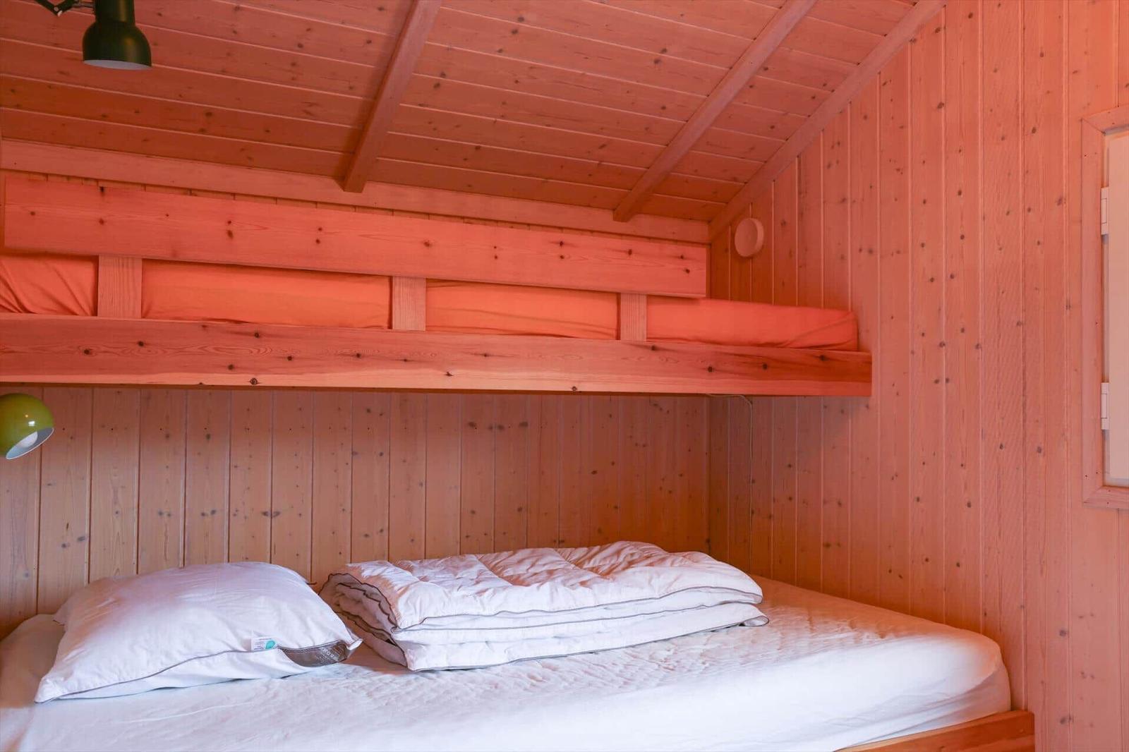 Room with two beds, wooden walls and ceiling, green lamp