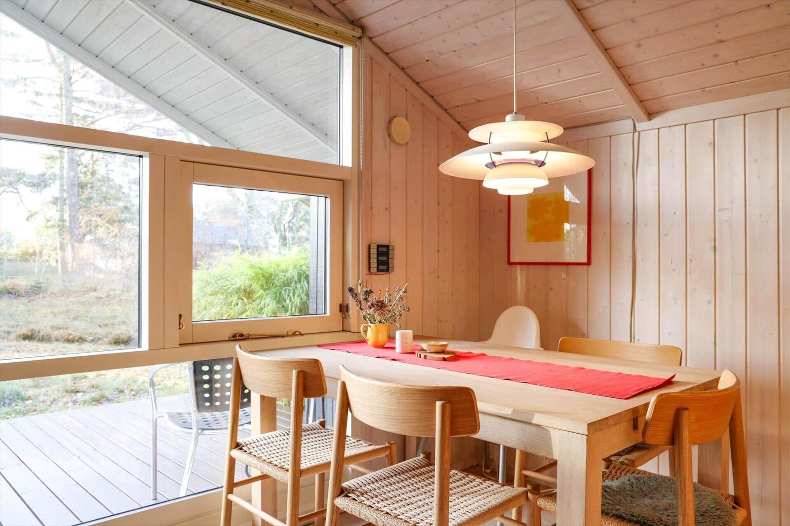 Dining room with wooden table, chairs, and large window to the garden.