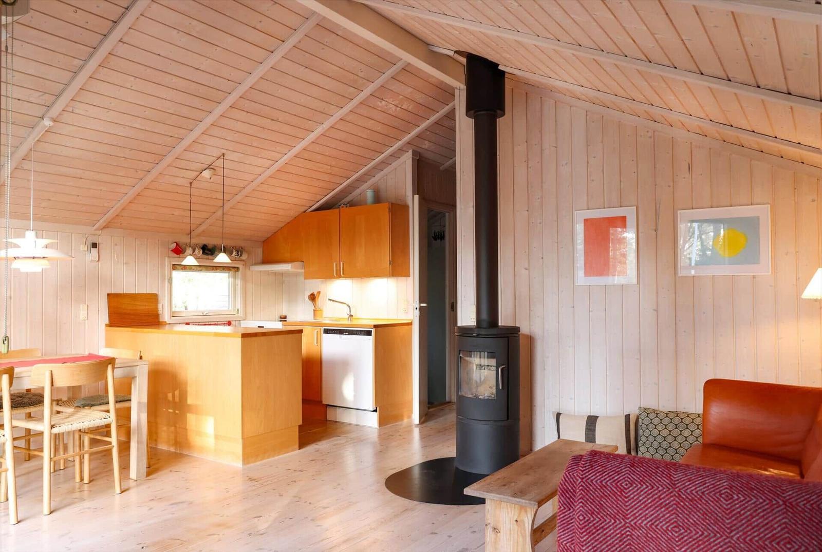 Living kitchen with wood walls, wood stove, and dining area.