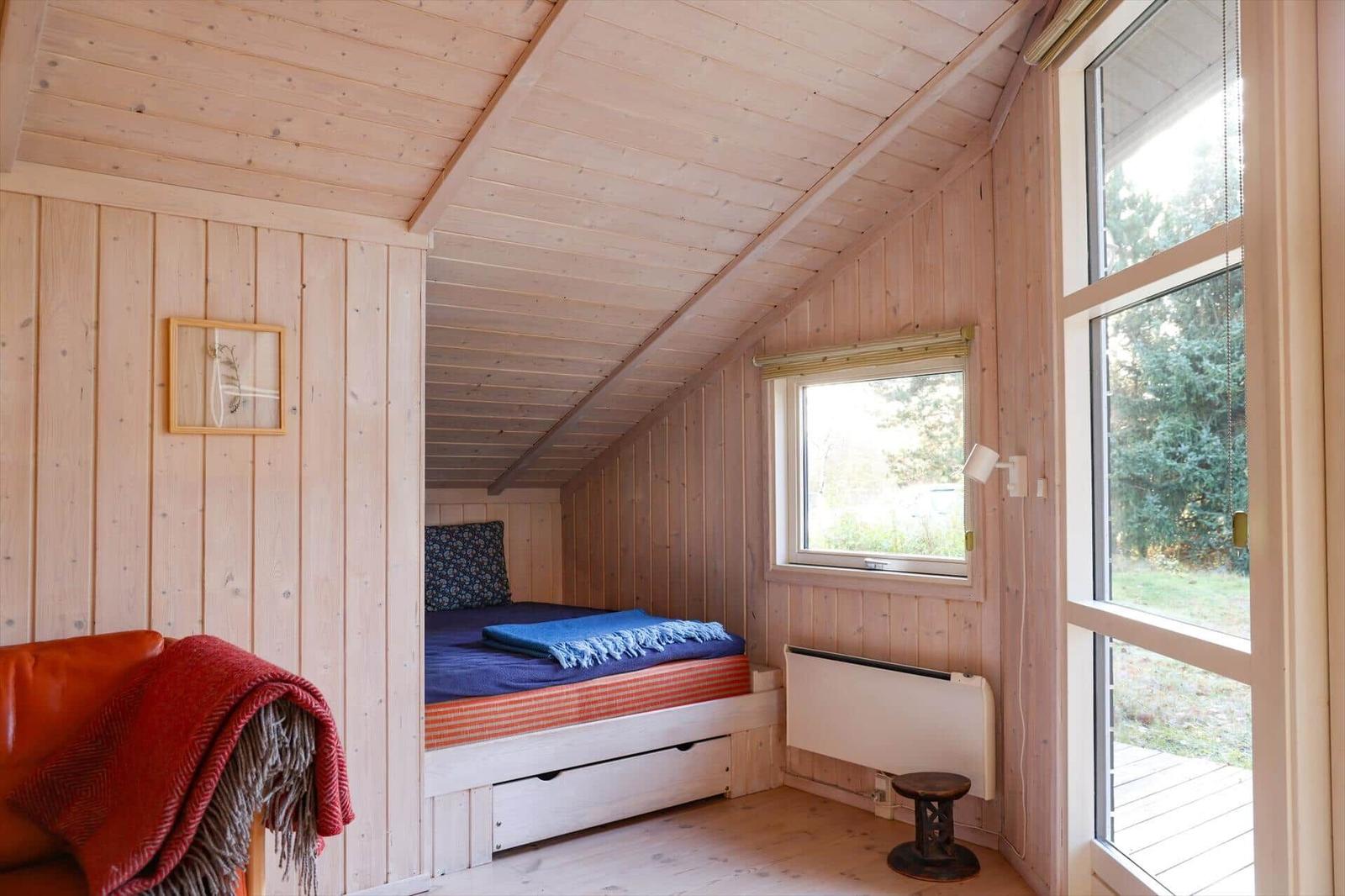 Bedroom with wooden walls, bed, and window to the outside.