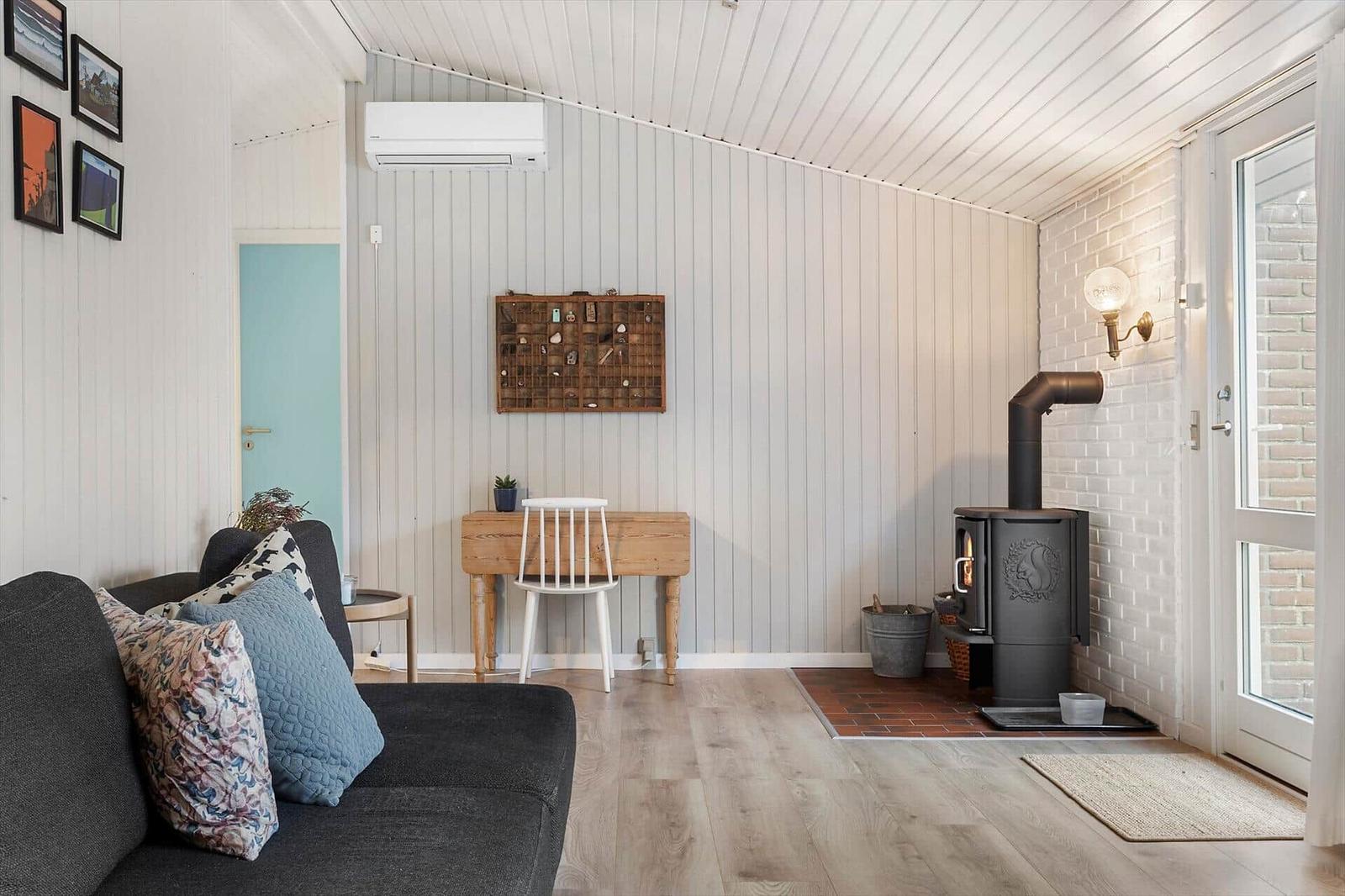 Wohnzimmer mit Sofa, Holztisch, Kaminofen und Holzboden.