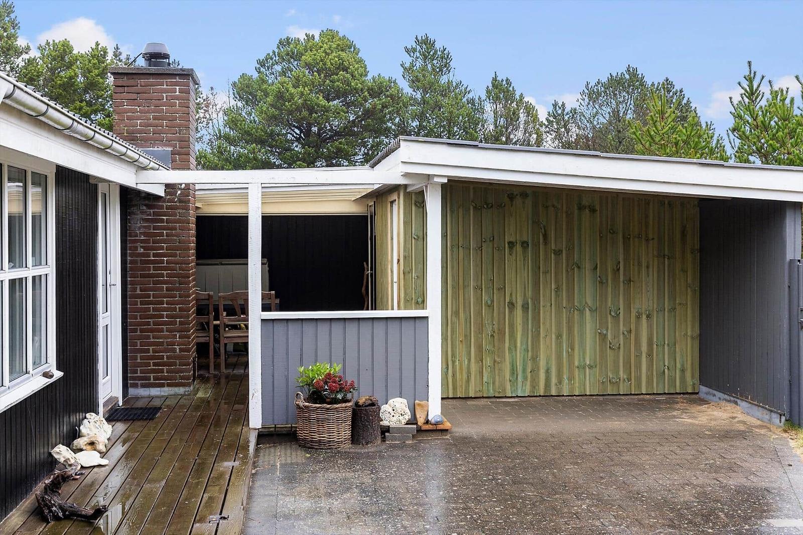 Haus mit Terrasse, Holzwand und Grillbereich im Freien.