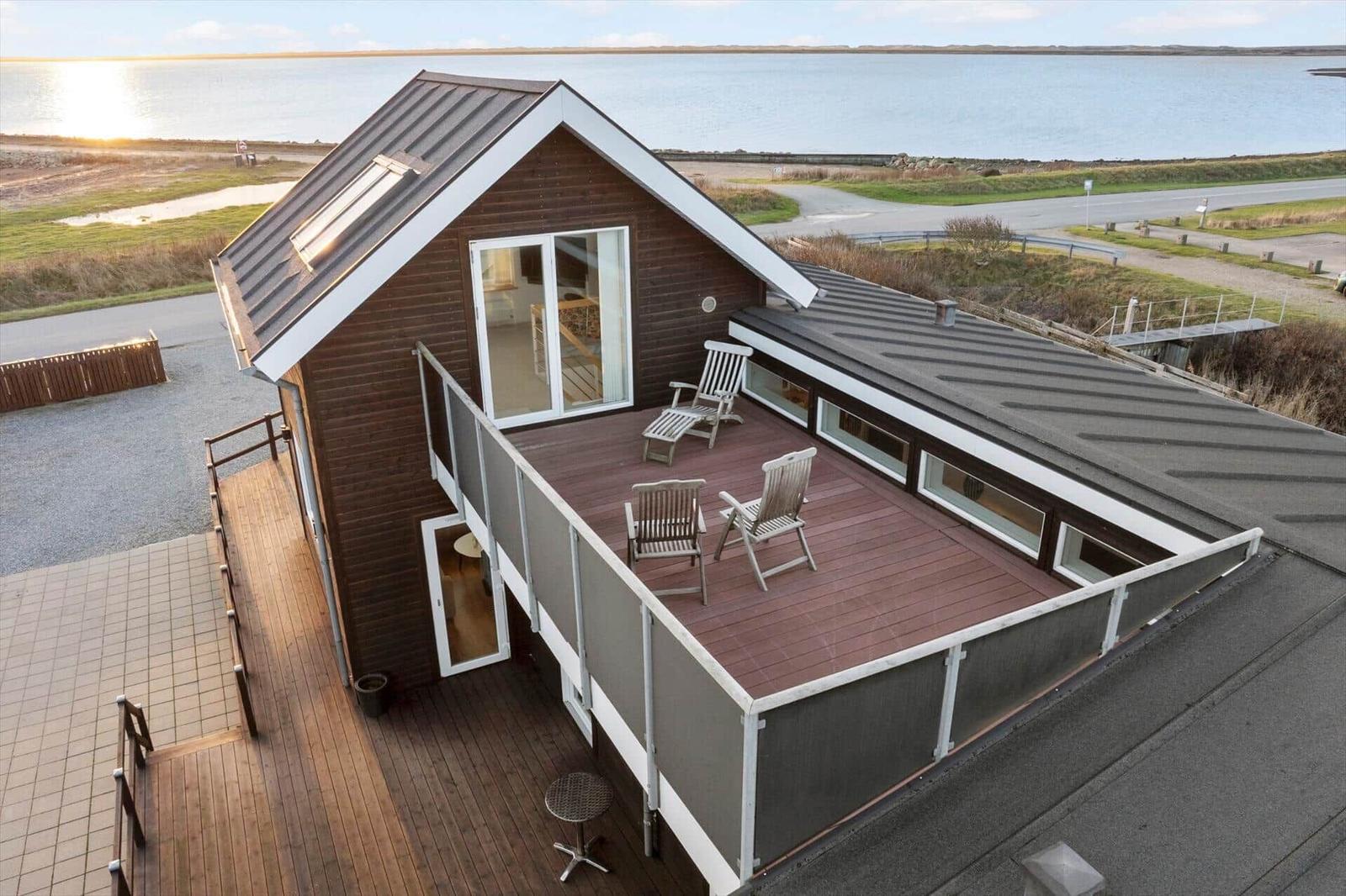 Modern villa with terrace and sea view. Wooden terrace with loungers and seating area.