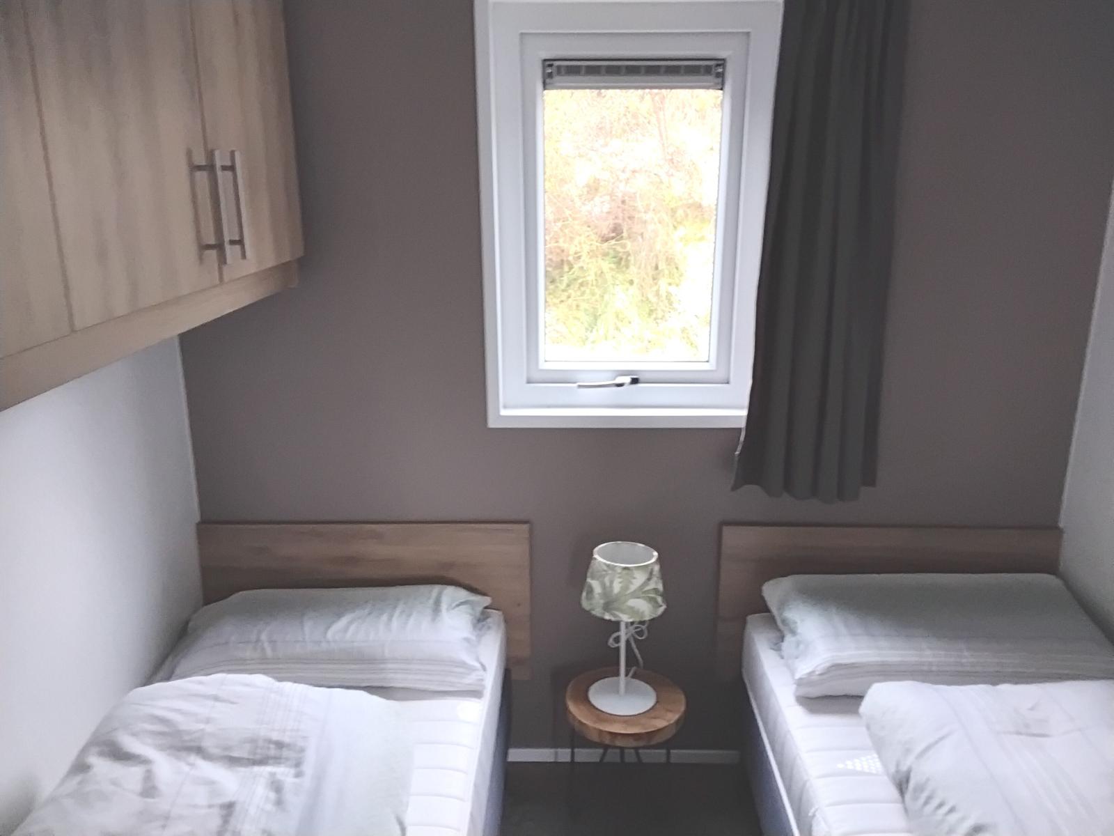 Zwei Einzelbetten mit Nachttisch und Fenster