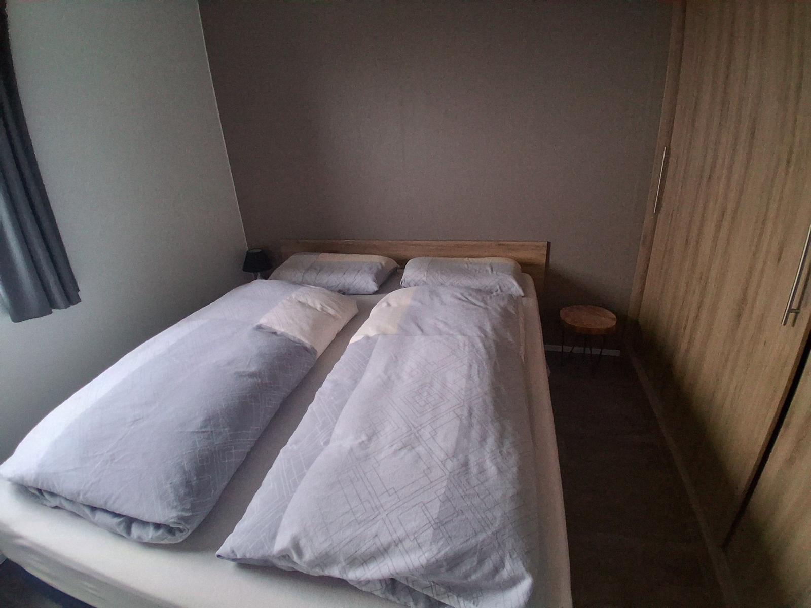 Schlafzimmer mit Doppelbett, Nachttisch und Kleiderschrank.