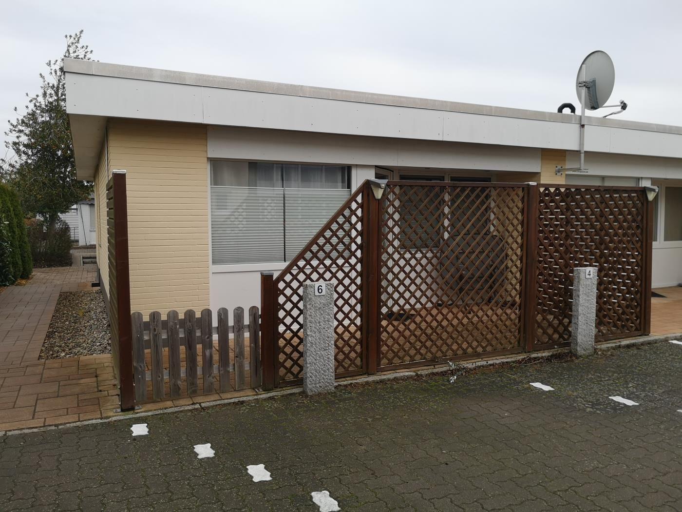 Moderne Ferienwohnung mit Holzgitterzaun und Satellitenanlage.