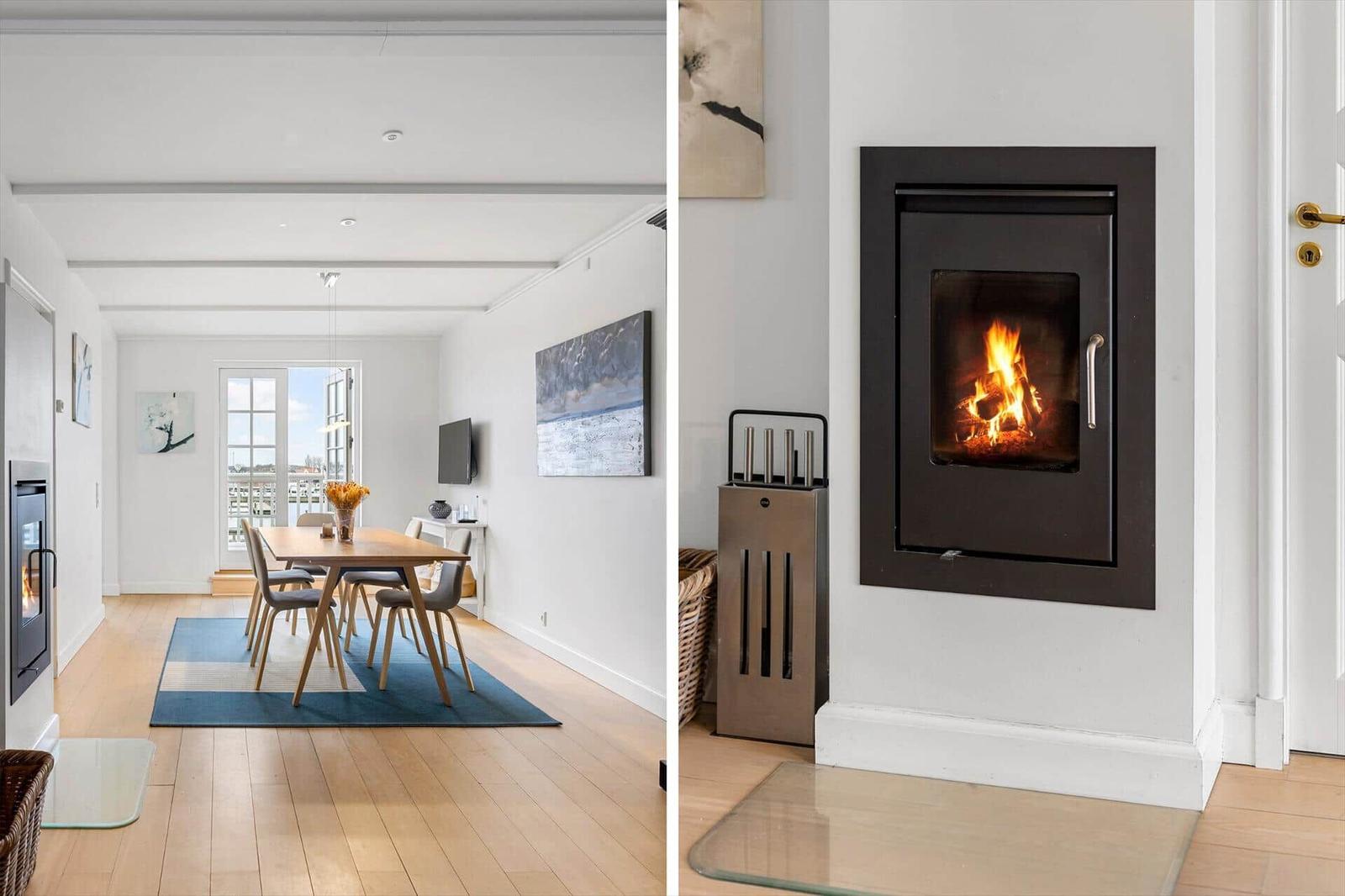 Dining area with table and chairs. Fireplace with burning wood.