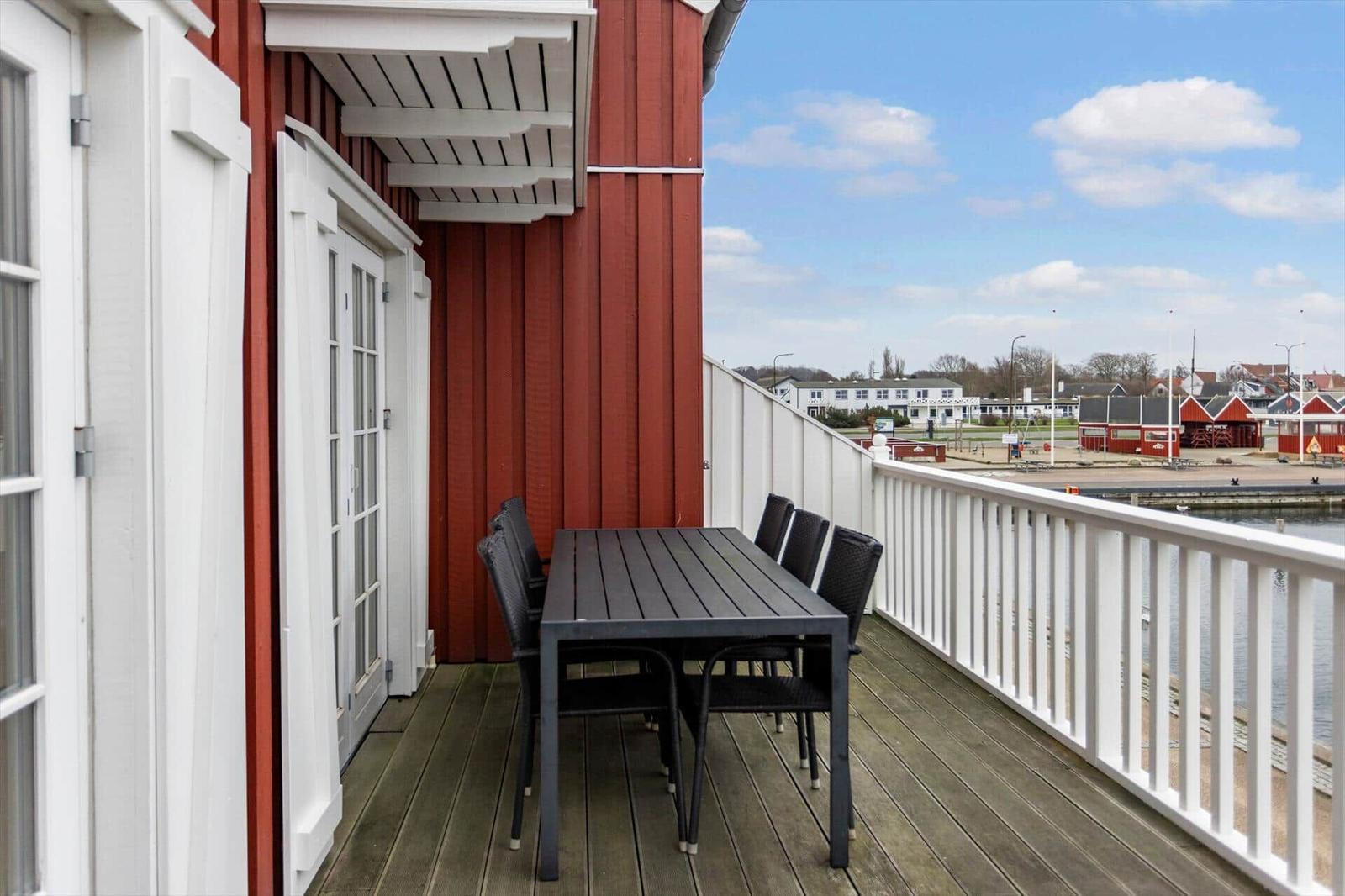Deck with table and chairs, view of water and harbor basin.