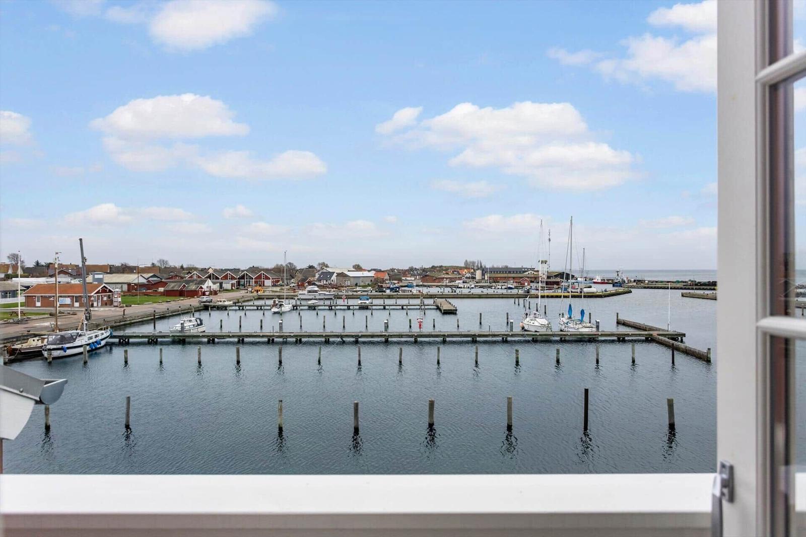 View of harbor with boats and houses under blue sky