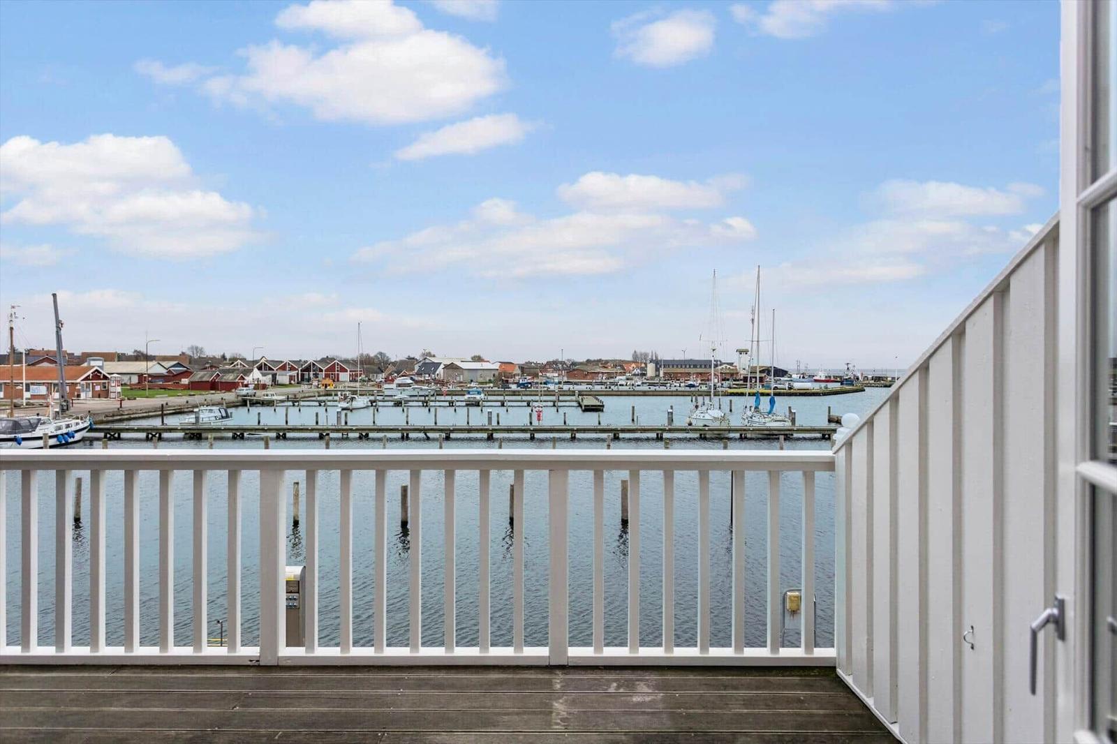 View of harbor with boats and red houses from balcony.