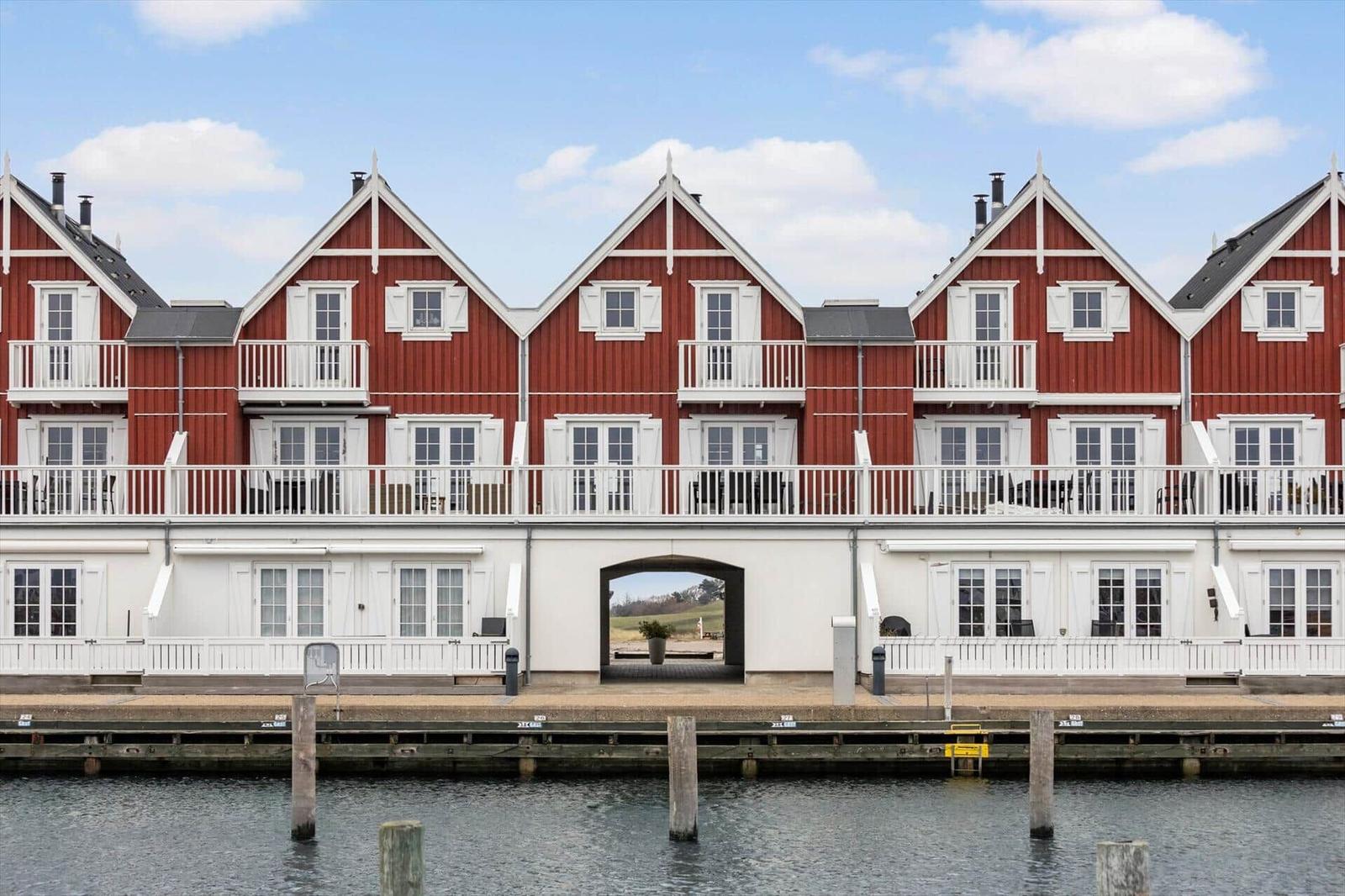 Red houses with white balconies stand by the water.