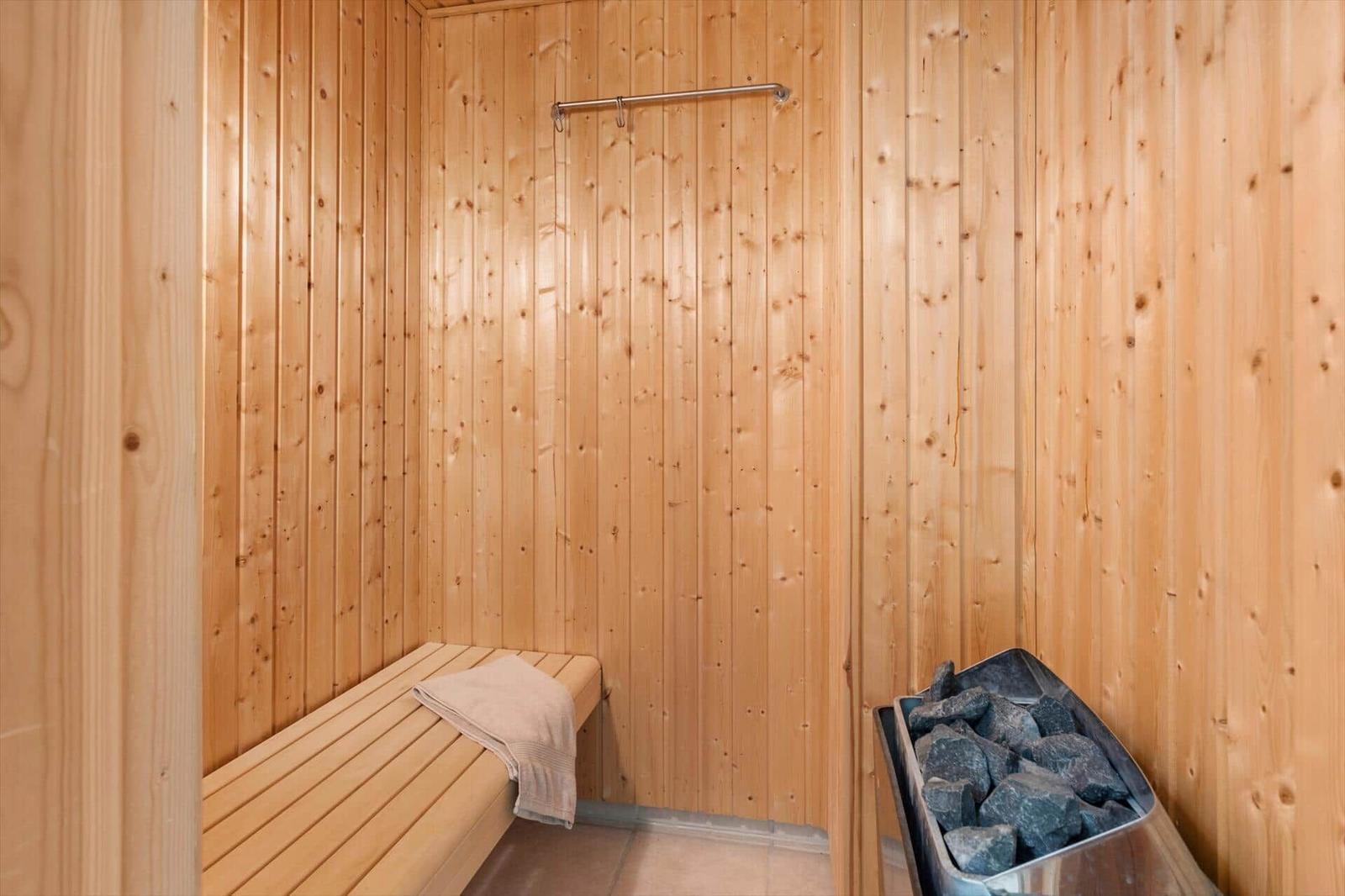 Sauna with wooden walls, bench, and stone tray