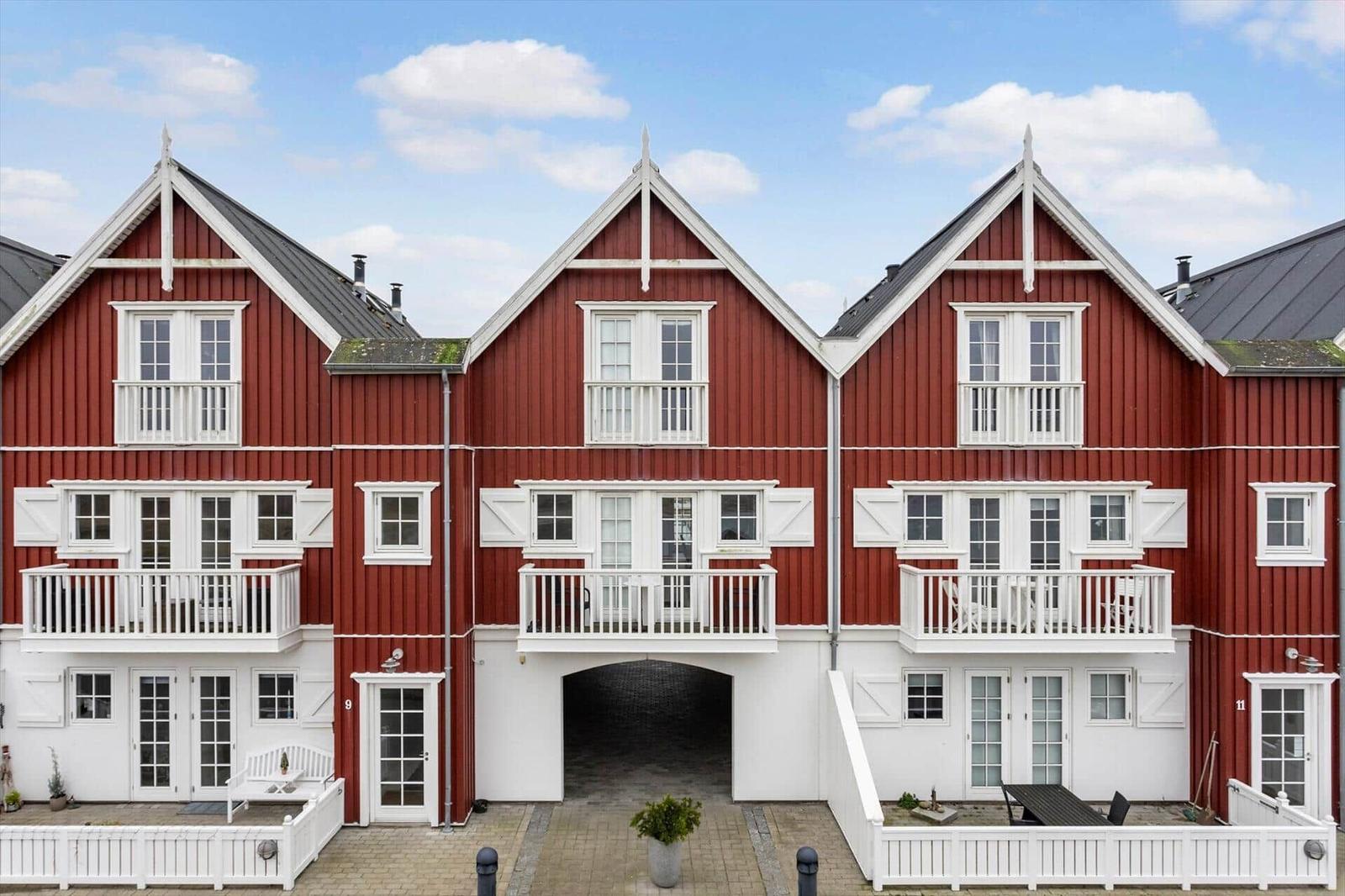 Red wooden houses with white balconies and window frames under blue sky.