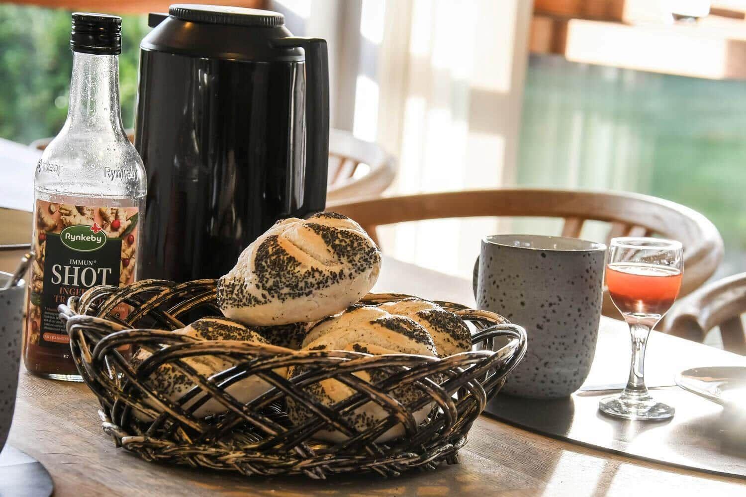 Table with bread basket, coffee pot, glasses, and bottle.