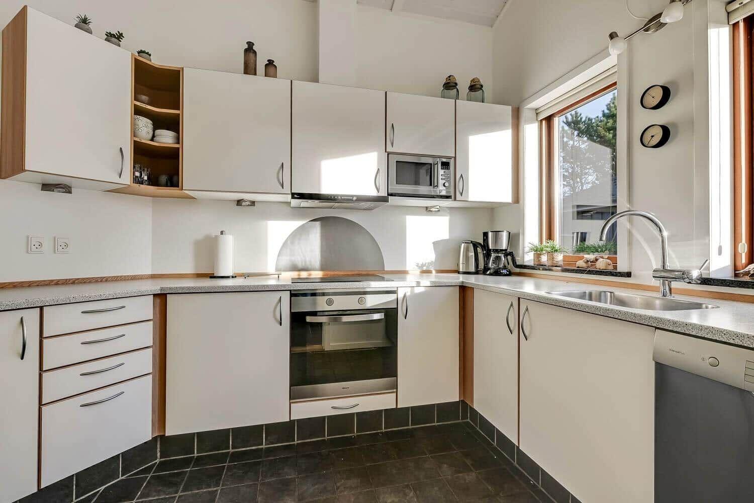 Kitchen with white cabinets, stainless steel appliances, and window with view outside.
