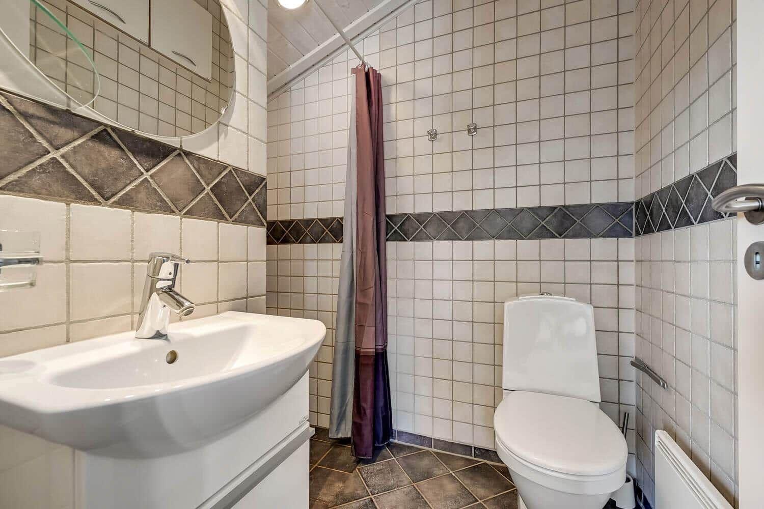 Bathroom with sink, toilet, and shower with curtain.
