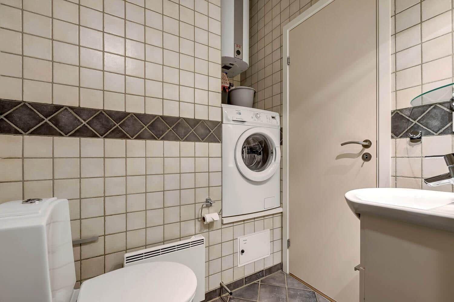 Bathroom with washing machine, toilet, and sink against the wall