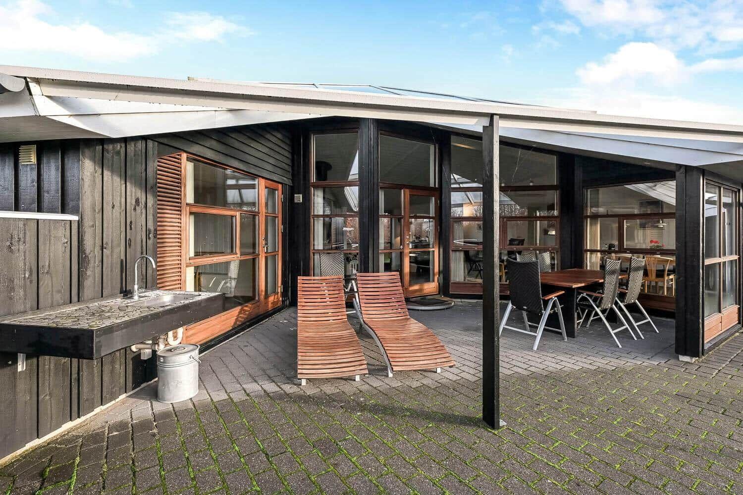 Terrace with lounge chairs and table. Outdoor area with sink and wooden wall.