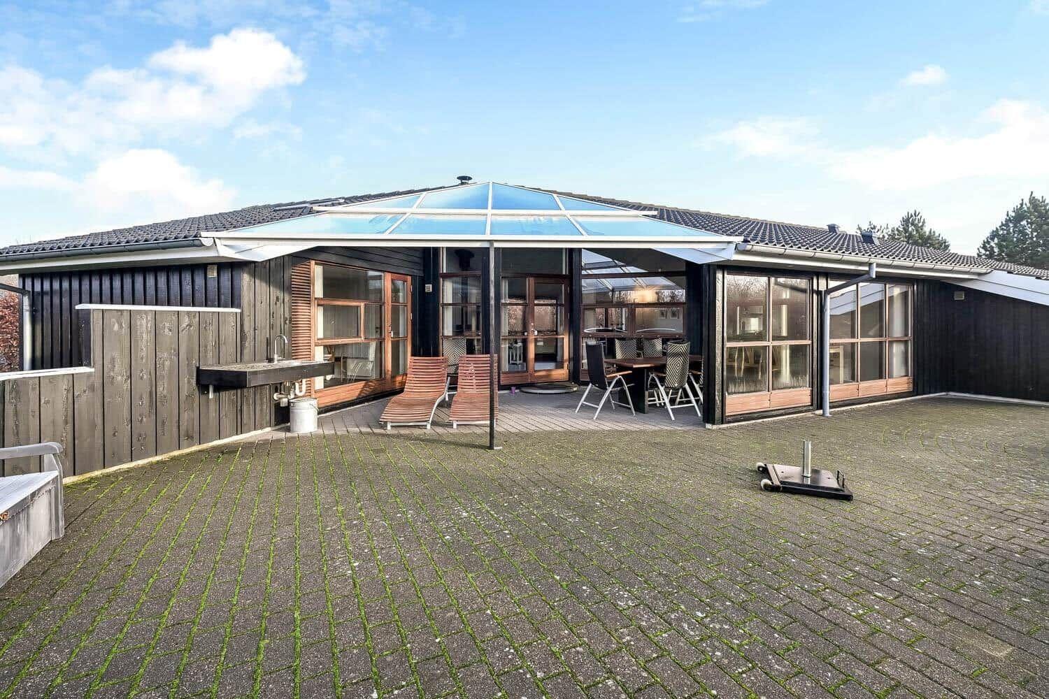 House with large courtyard, terrace, and glass roof. Outdoor grill and lounge chairs are available.