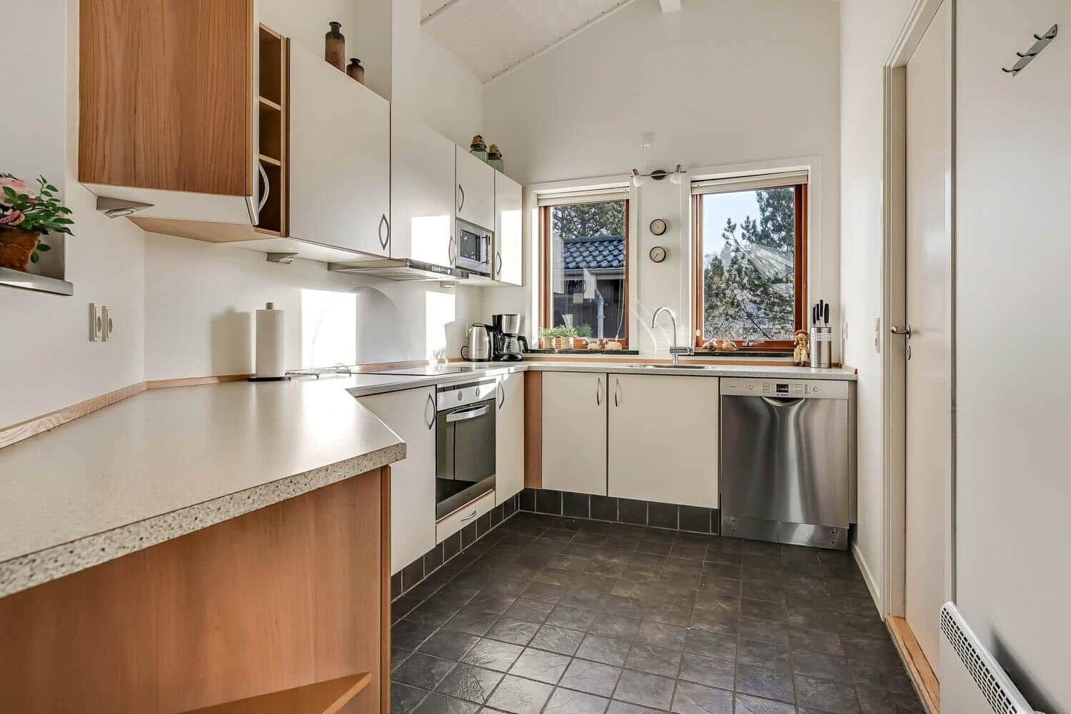 Kitchen with countertops, sink, stove, and dishwasher. Windows offer view of outside area.