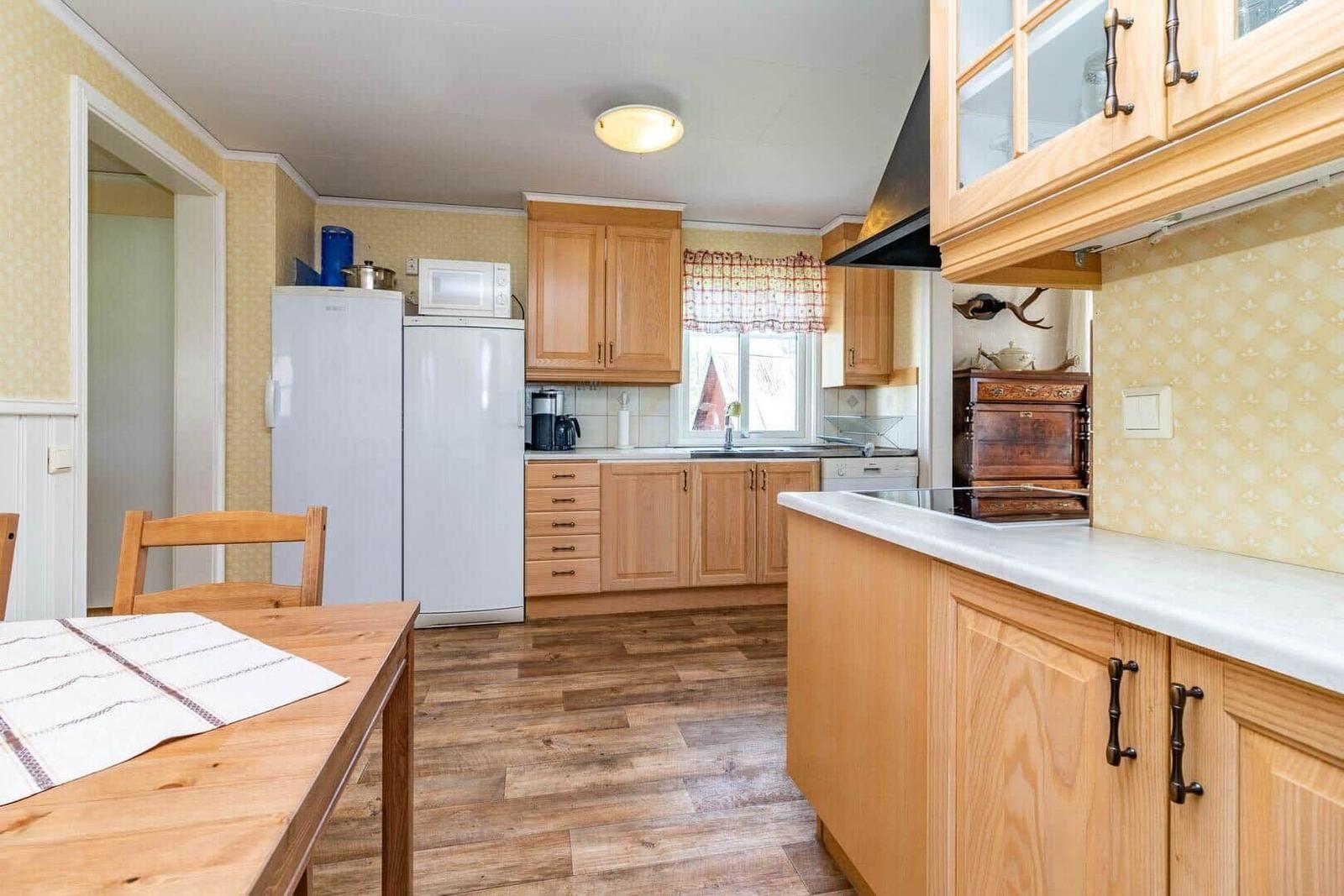 Küche mit Holzmöbeln, Kühlschrank, Spüle und Esstisch.
