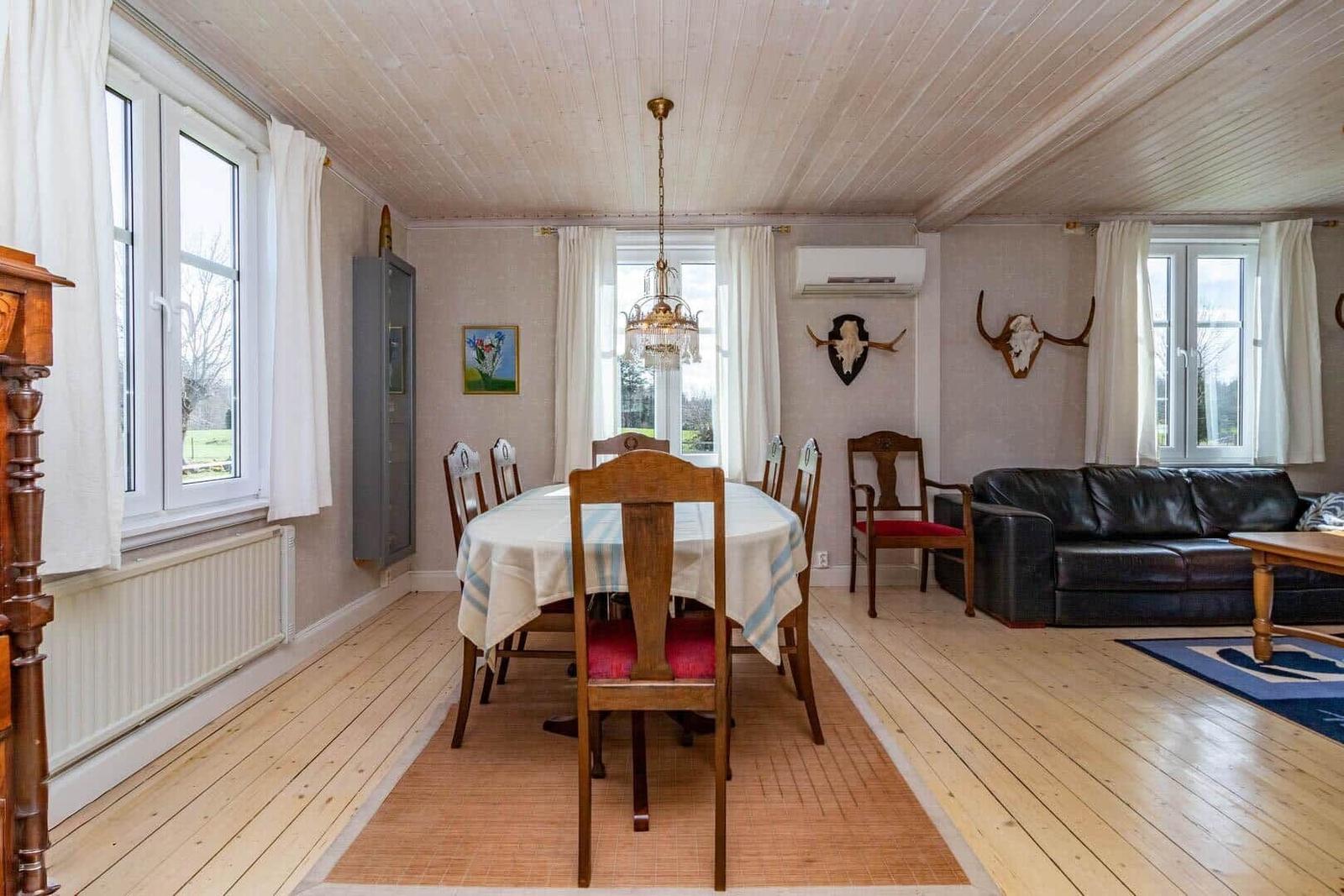 Esszimmer mit Esstisch, Stühlen und Wohnbereich mit Sofa und Wanddekoration.