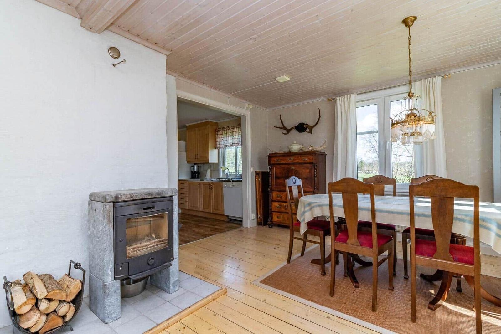 Esszimmer mit Holztisch, Stühlen und Kamin. Küche im Hintergrund.