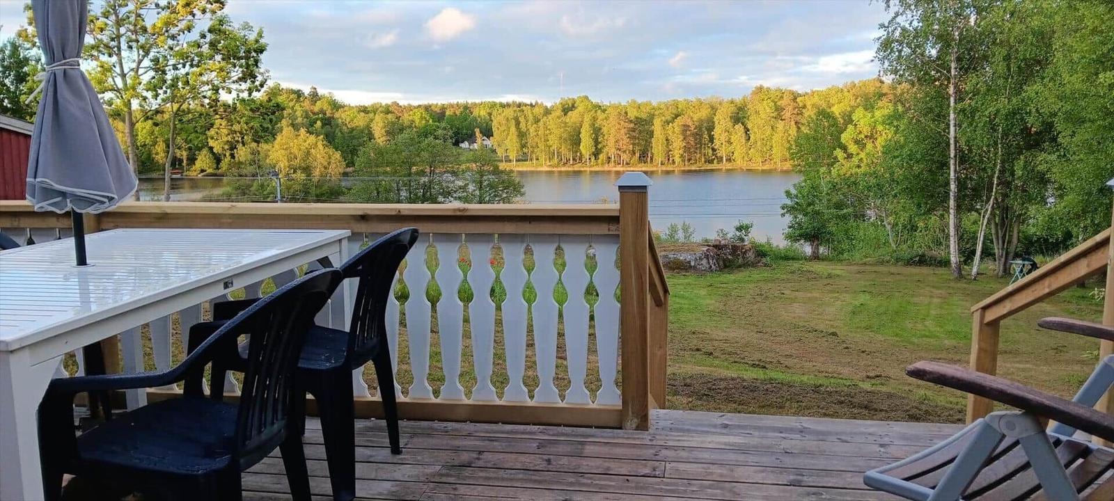 Terrasse mit Tisch, Stühlen und Blick auf einen See.