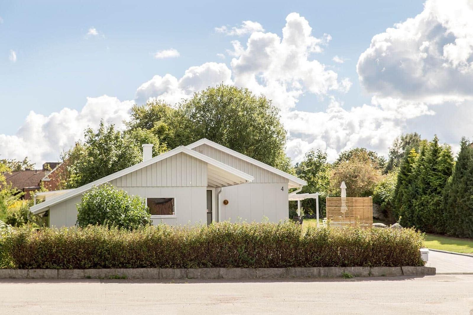Moderne Villa mit Garten, Terrasse und Sonnenschirm. Umgeben von Bäumen und Sträuchern.