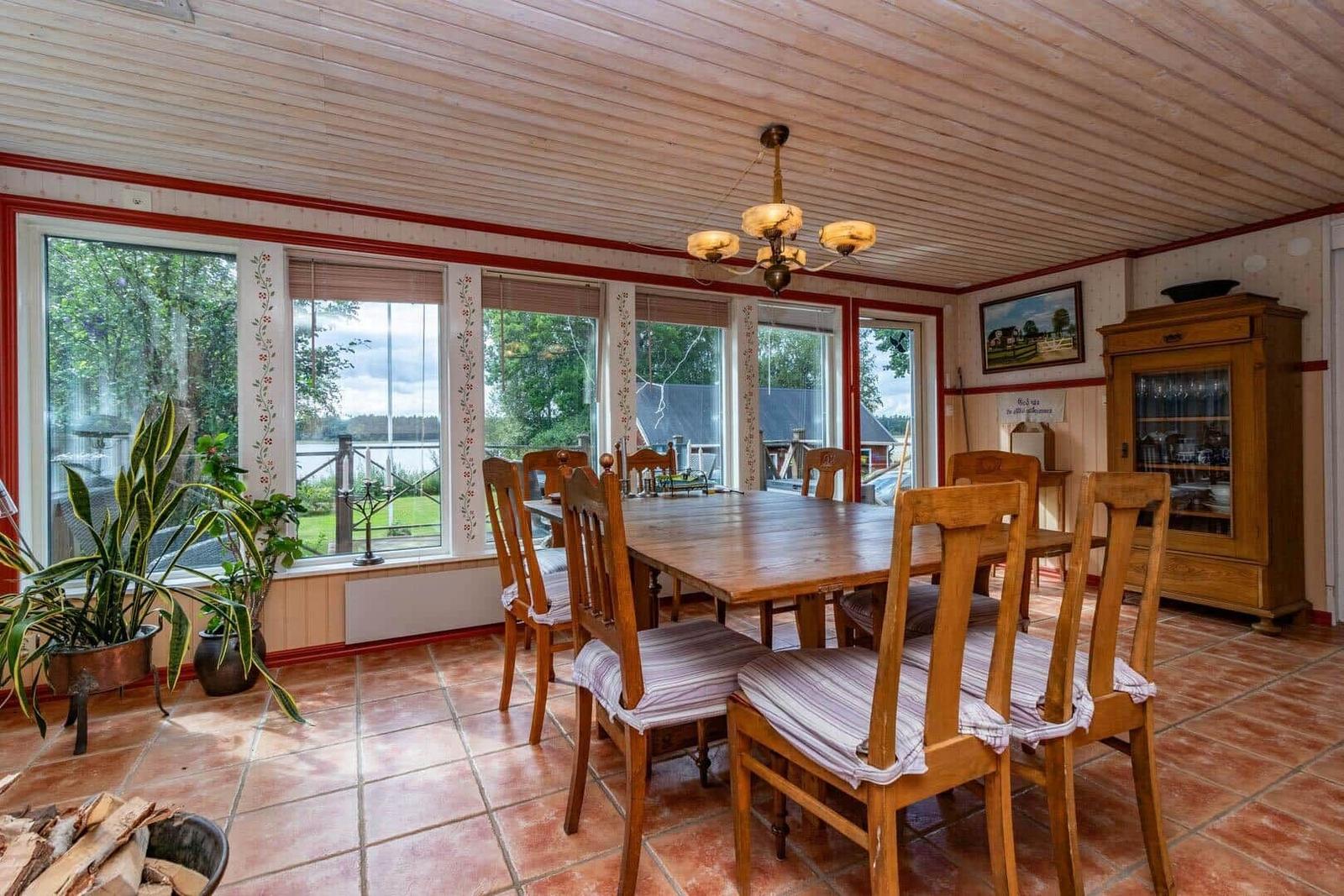 Esszimmer mit Holztisch, Stühlen und Fenstern zum See