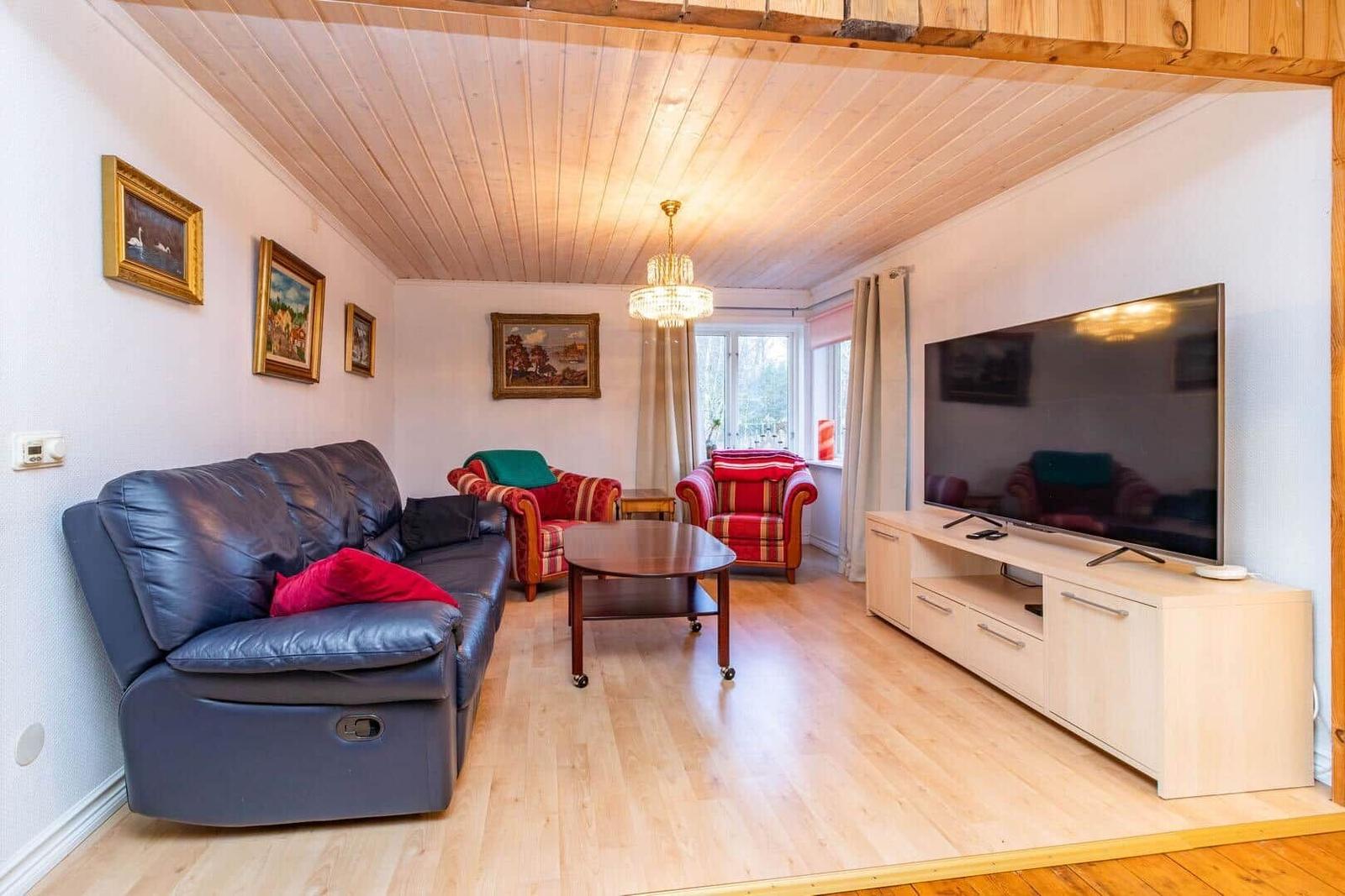 Wohnzimmer mit Sofa, Sesseln, TV und Holzboden.