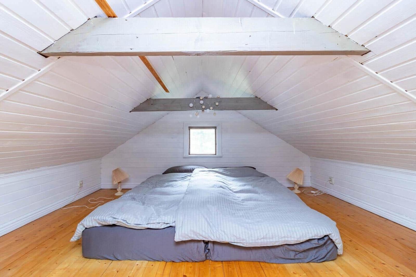 Schlafzimmer mit Dachschrägen, Holzboden und Bett unter Dach