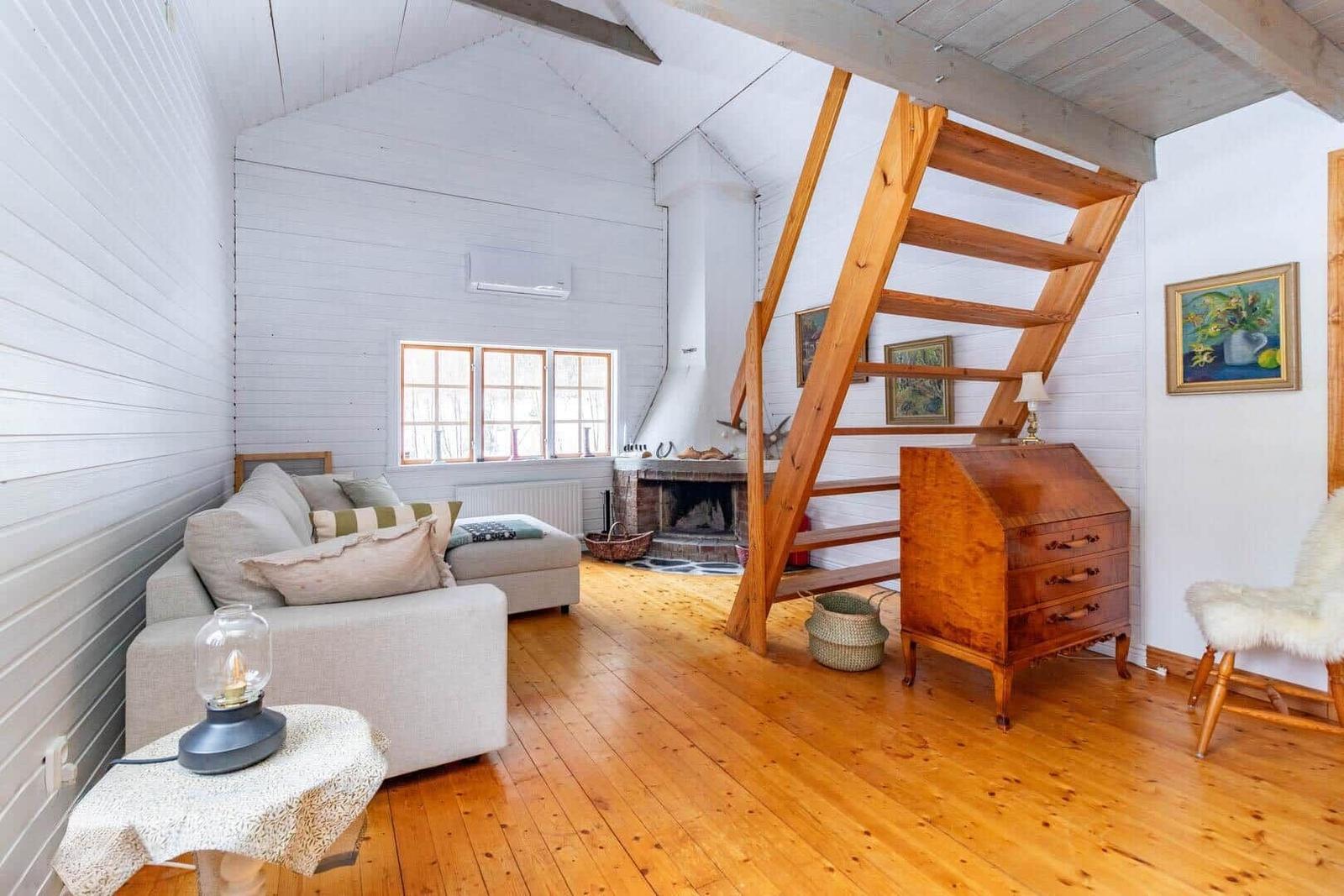 Wohnzimmer mit Sofa, Kamin und Holztreppe zu einer oberen Etage.
