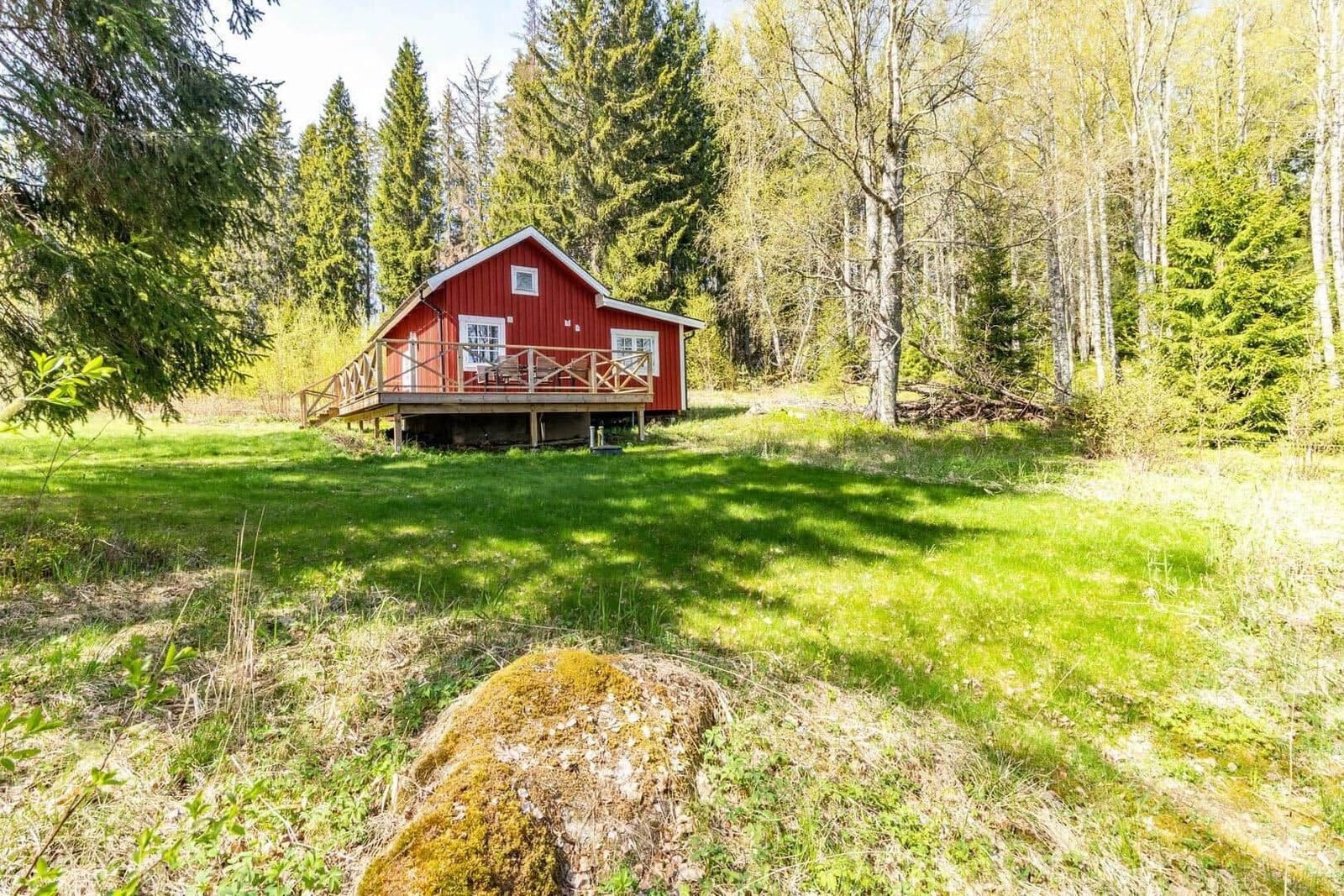 Rotes Holzhaus mit Veranda in grüner Umgebung