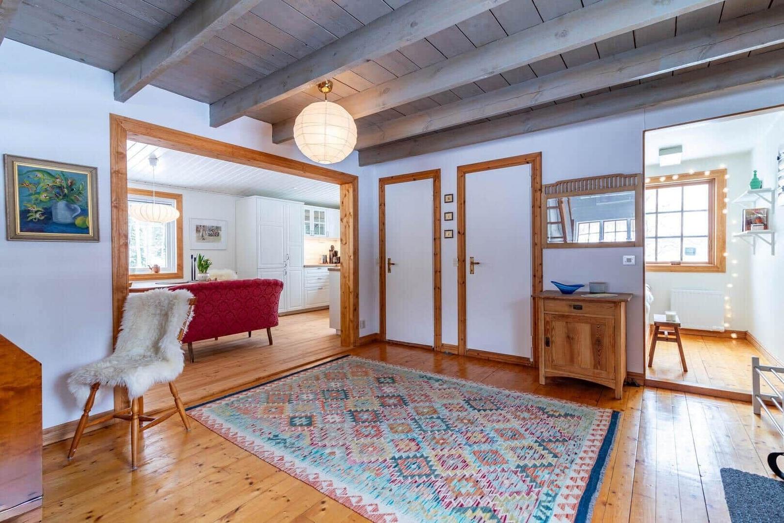 Eingangsbereich mit Holzboden, Teppich und Sitzgelegenheit. Blick in Küche und Schlafzimmer.