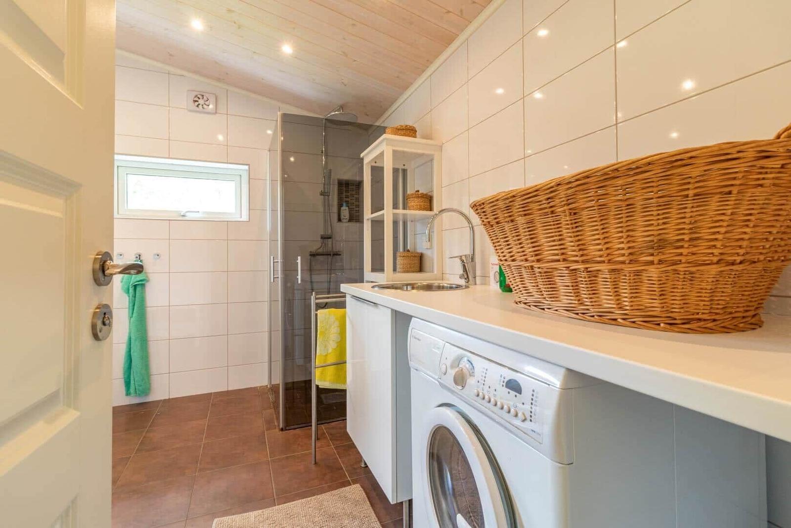 Bathroom with shower, washing machine, and sink with basket.