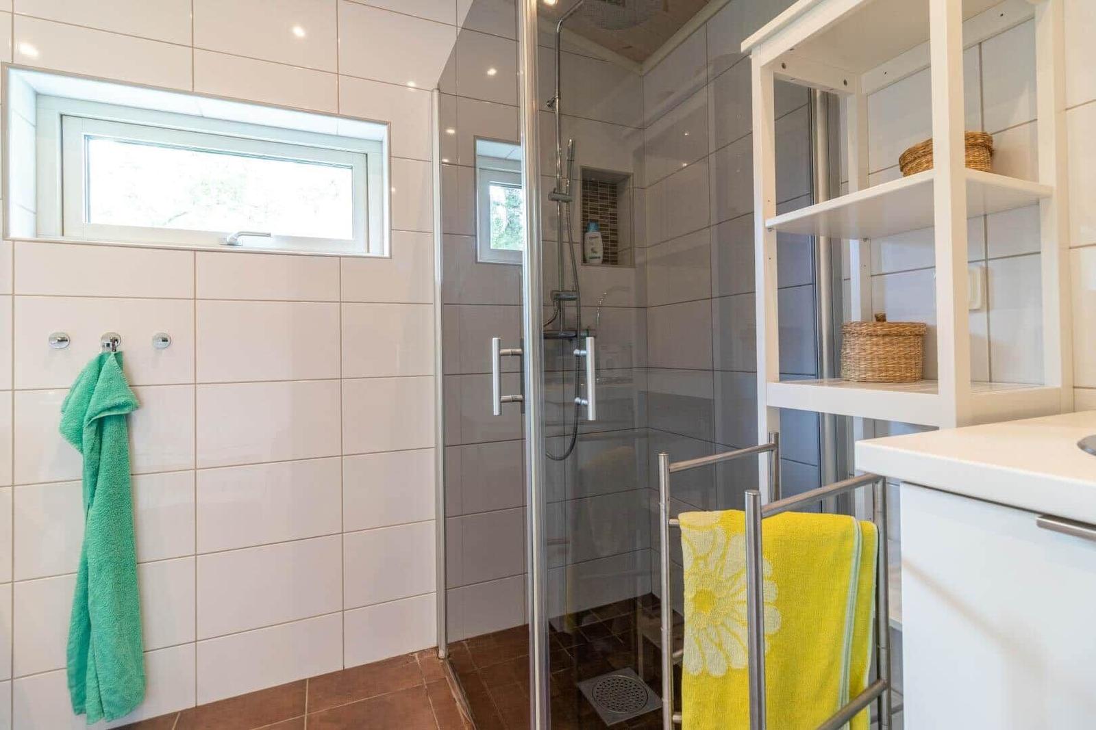 Bathroom with shower, window, and towel racks.