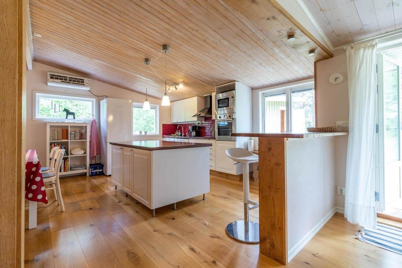 Kitchen with wooden floor, white cabinets, and kitchen island with bar height.