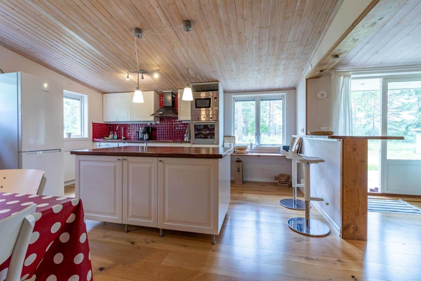 Kitchen with wooden ceiling, red tile backsplash, and island with wooden countertop.