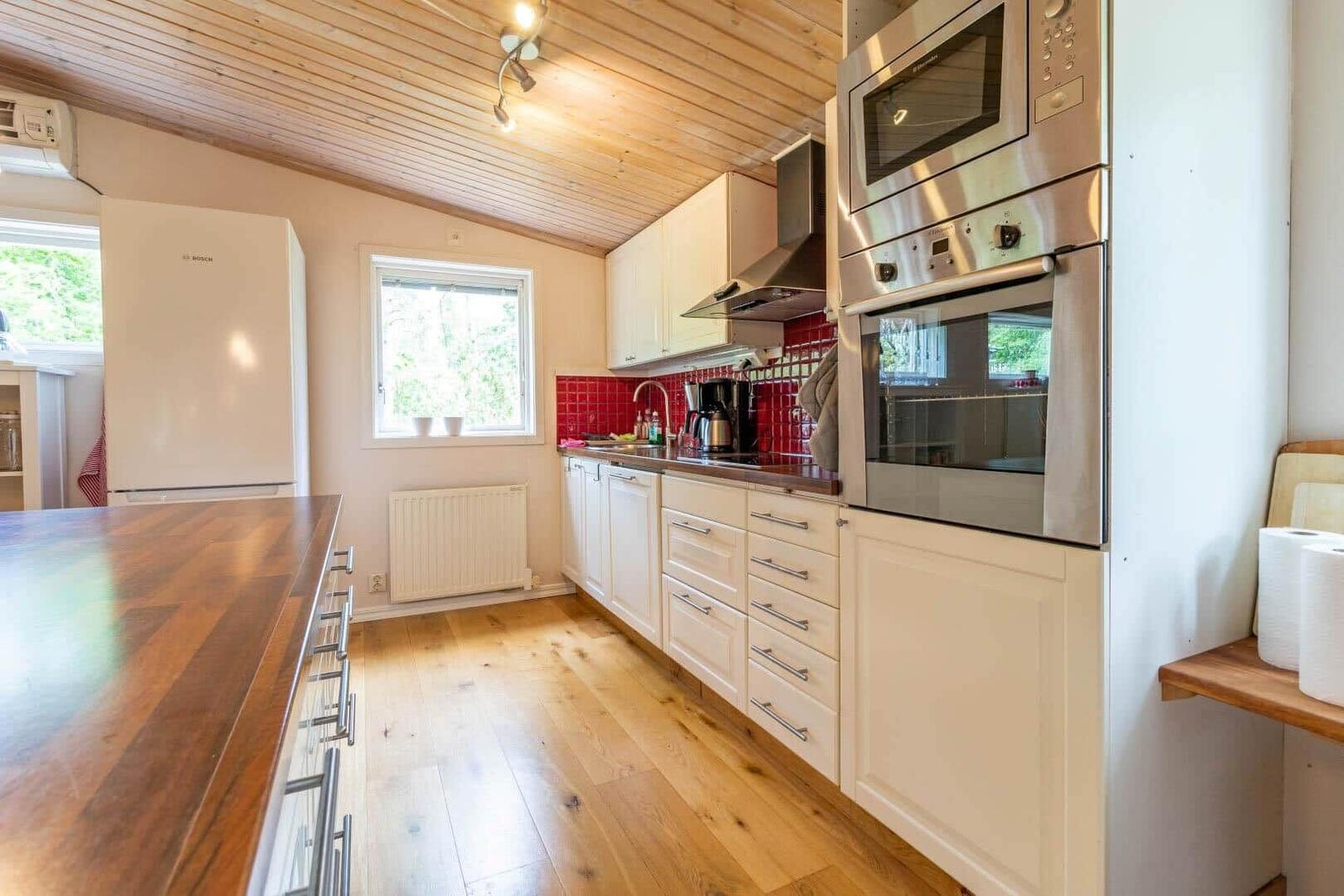 Kitchen with wooden floor, white cabinets, and stainless steel appliances.