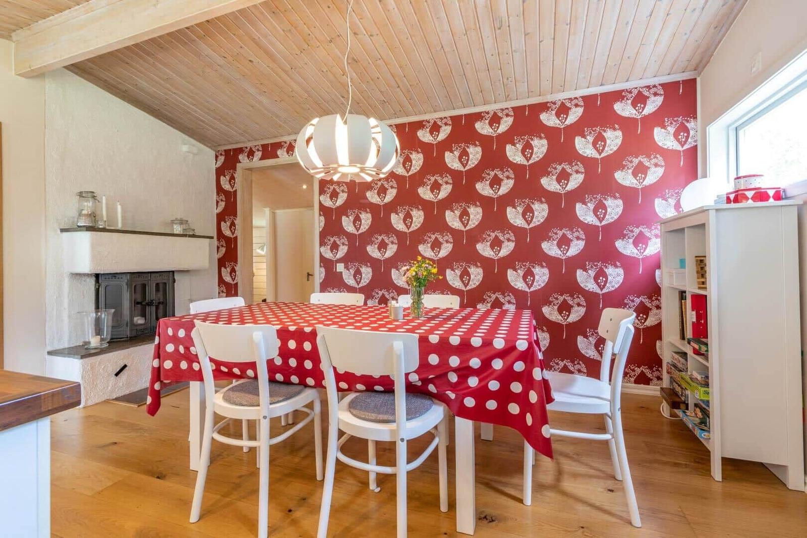 Dining room with table, chairs, red wallpaper, and wooden ceiling.