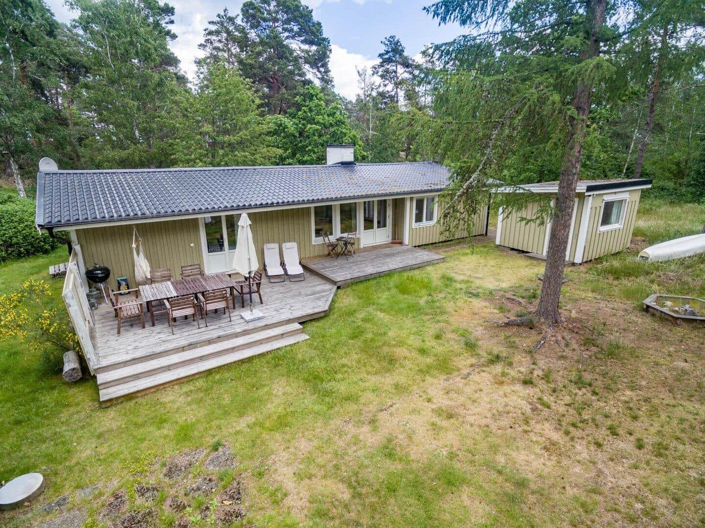 House with terrace, grill and garden in the forest. Wooden terrace with table, chairs and sun loungers.