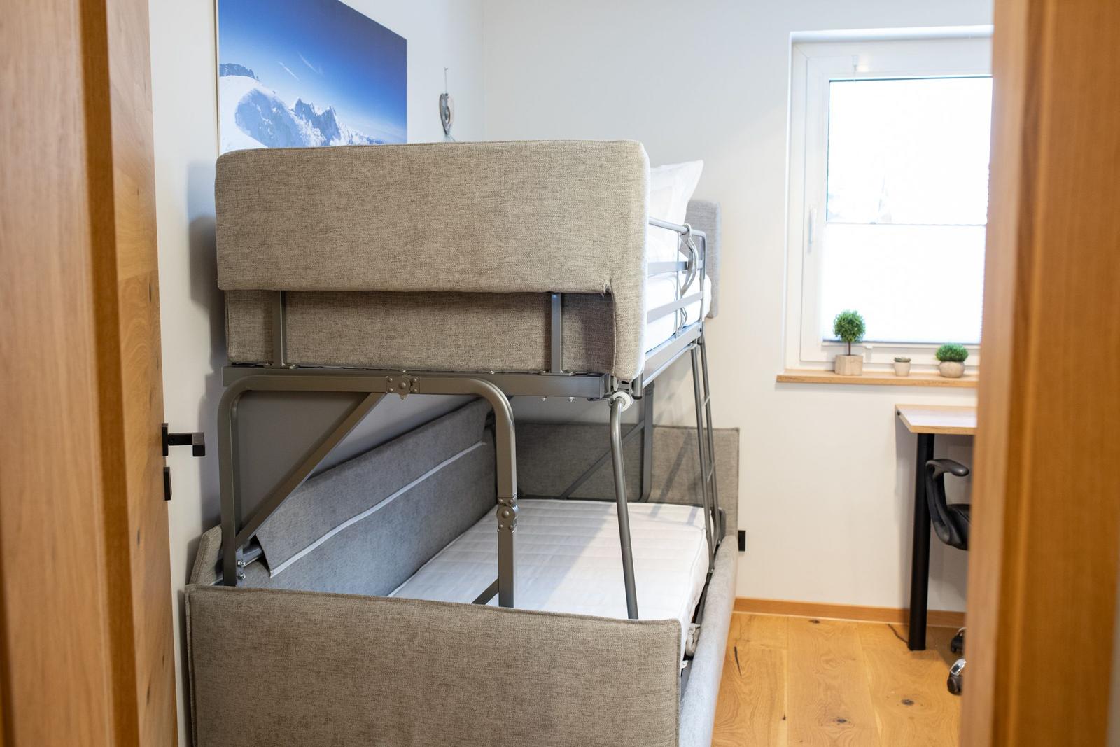 Zimmer mit Doppelstockbett, Schreibtisch und Fenster