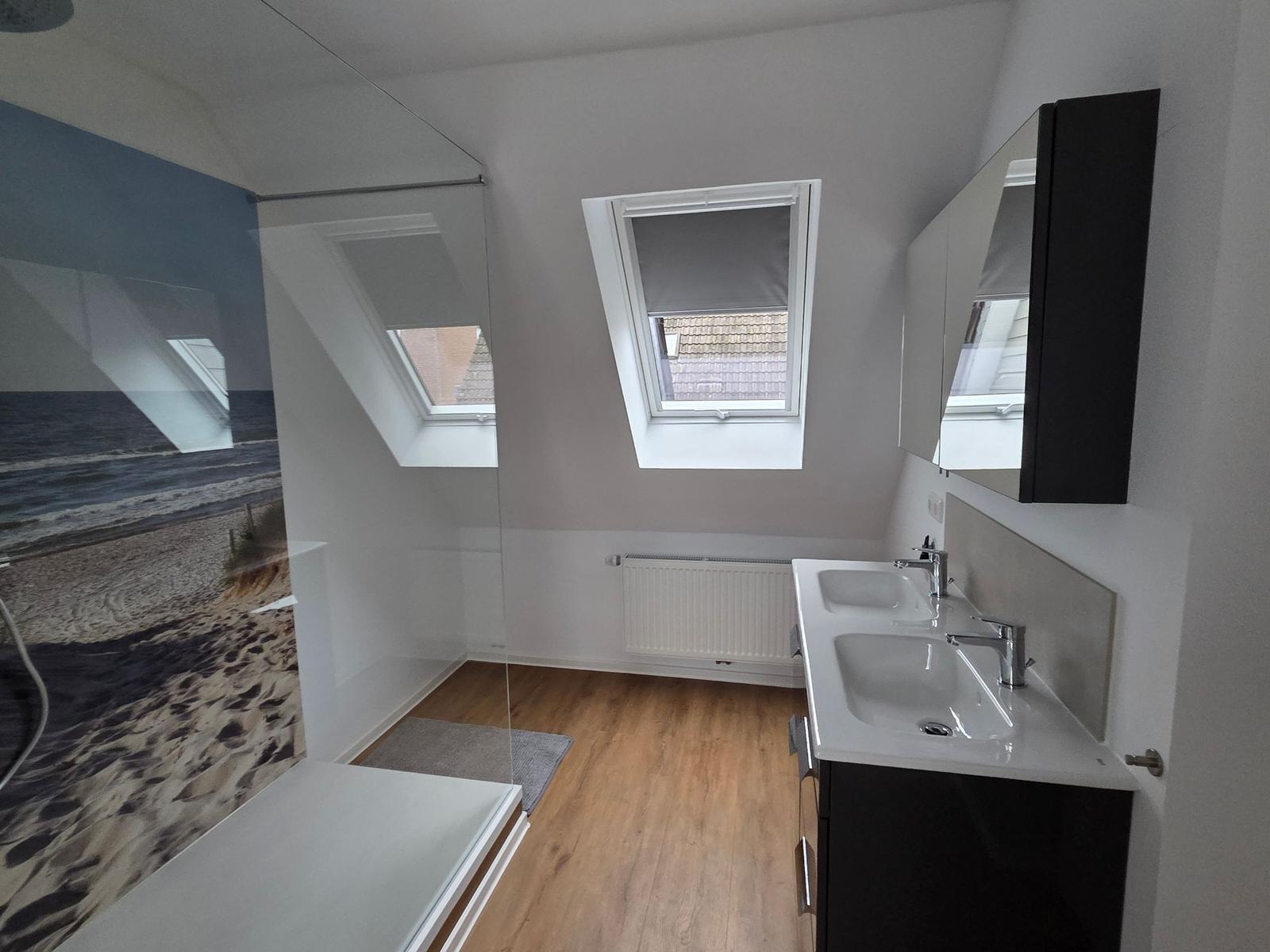 Badezimmer mit Dusche, Waschbecken und Dachfenstern.